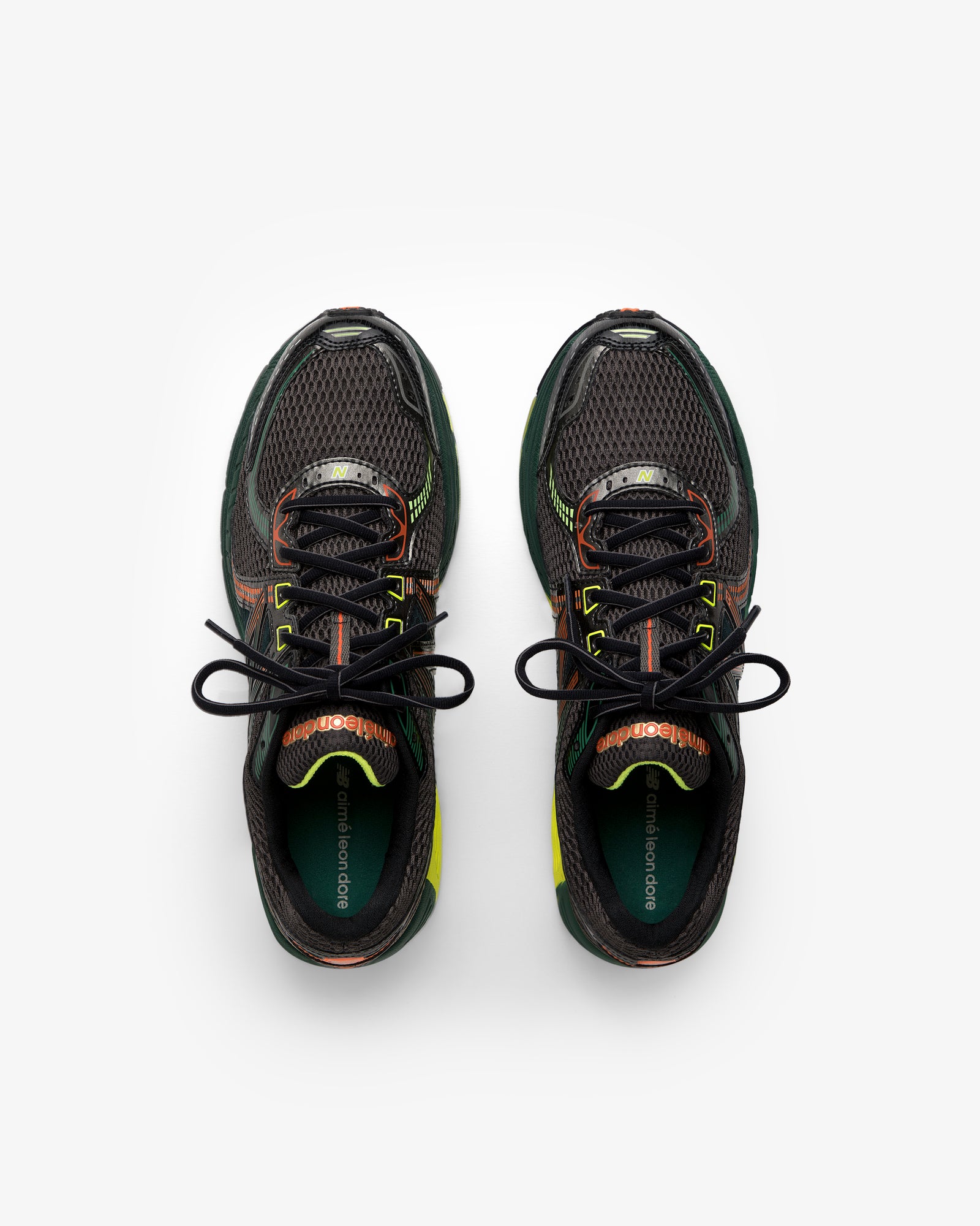 ALD / New Balance 860v2 black sneakers with green, orange, and yellow accents, top view on white background.