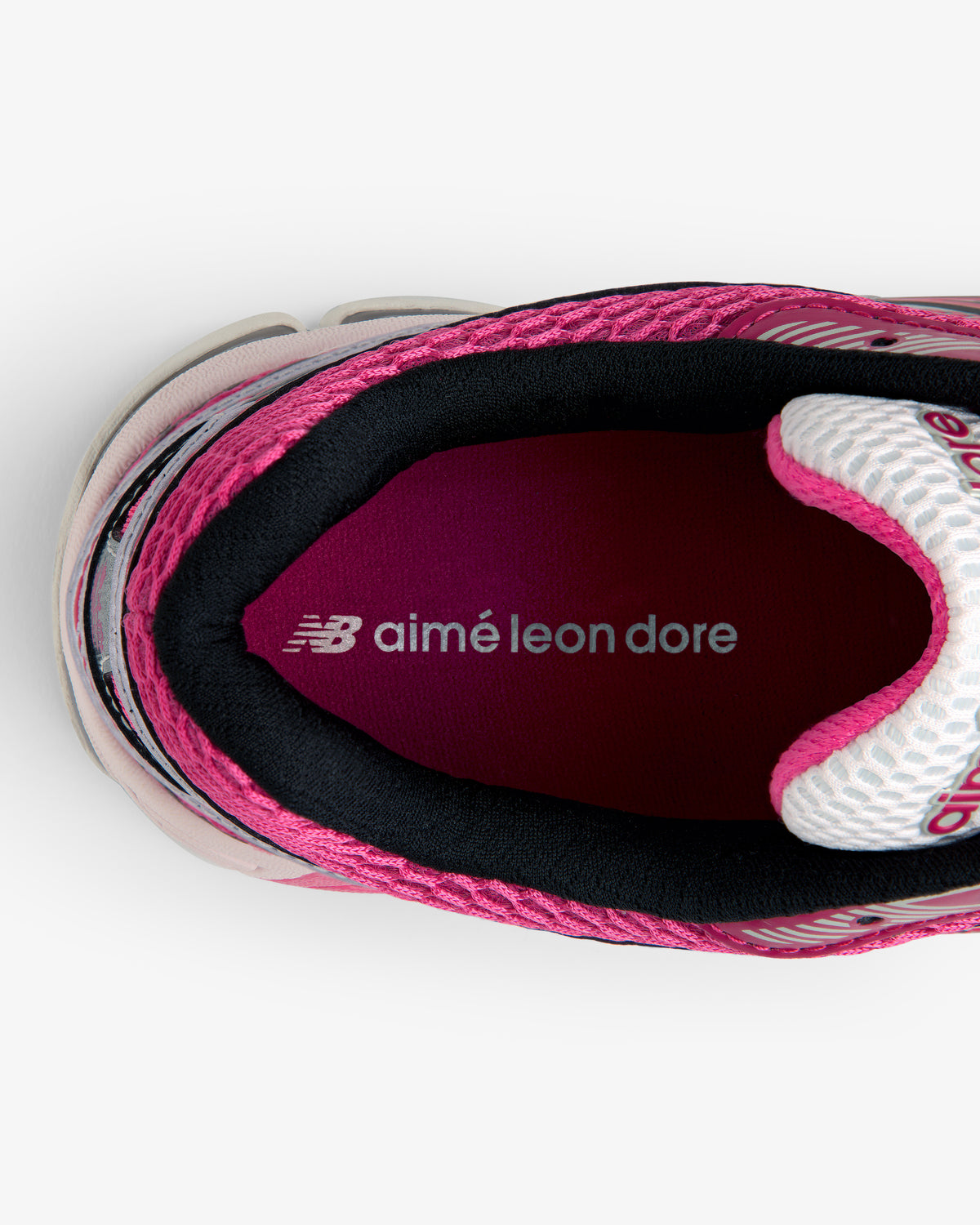 Top view of a pink ALD / New Balance 860v2 sneaker with aimé leon dore text on the maroon insole.