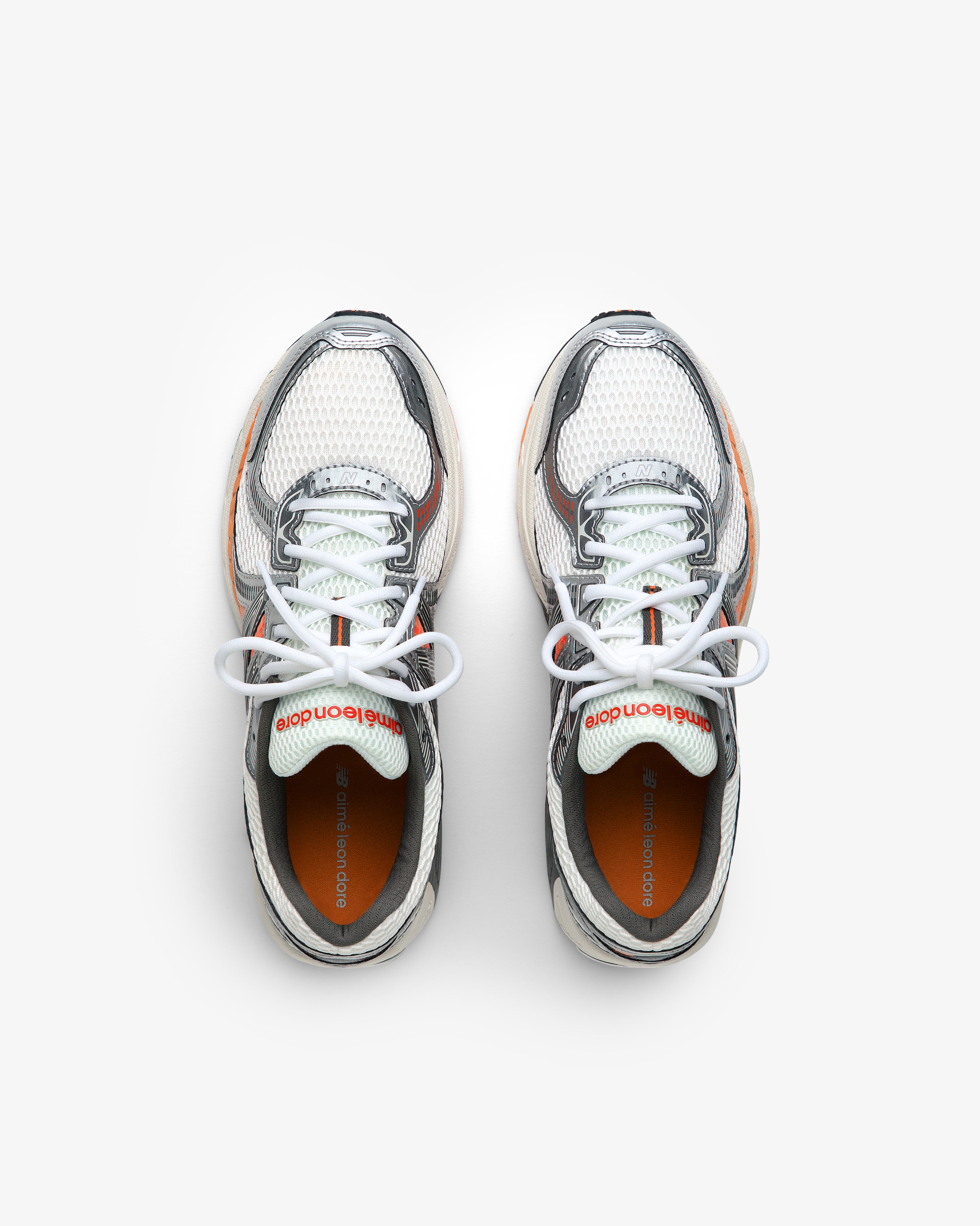 ALD / New Balance 860v2 white mesh sneakers with gray and orange accents, top view on a white background.