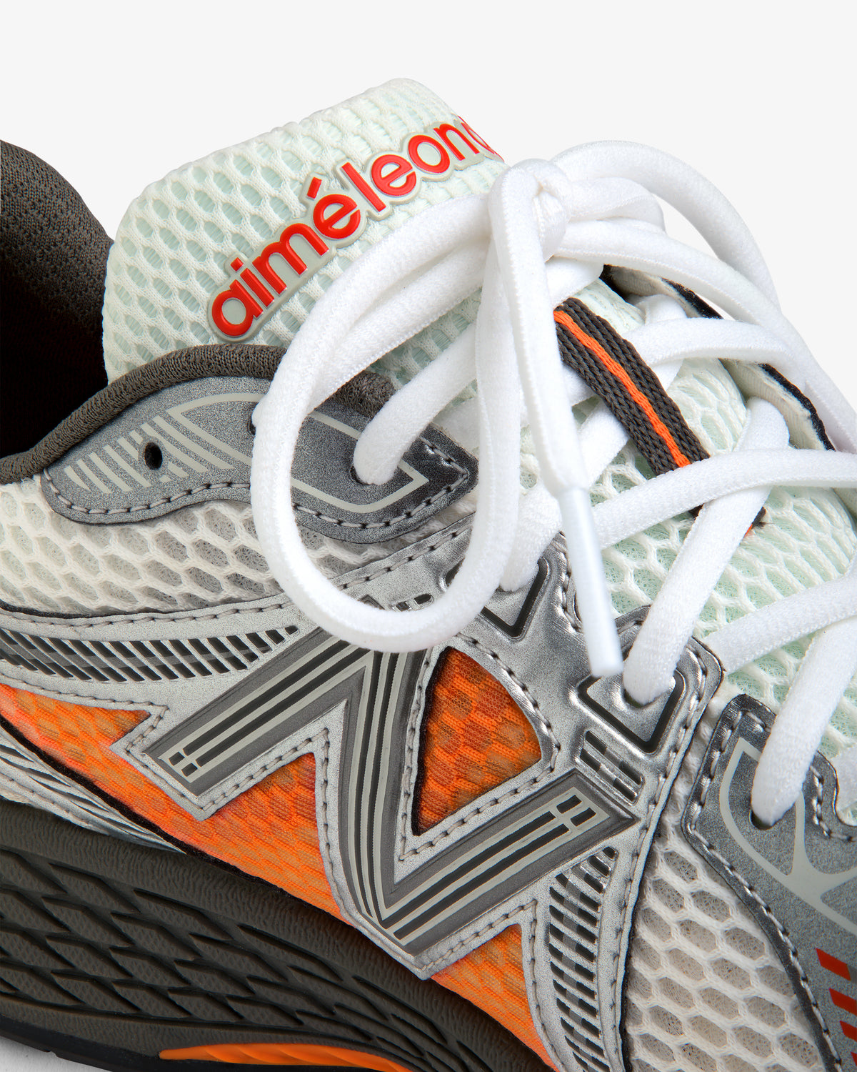 Close-up of the ALD / New Balance 860v2 with white laces, mesh texture, orange accents, and Aimé Leon text on tongue.