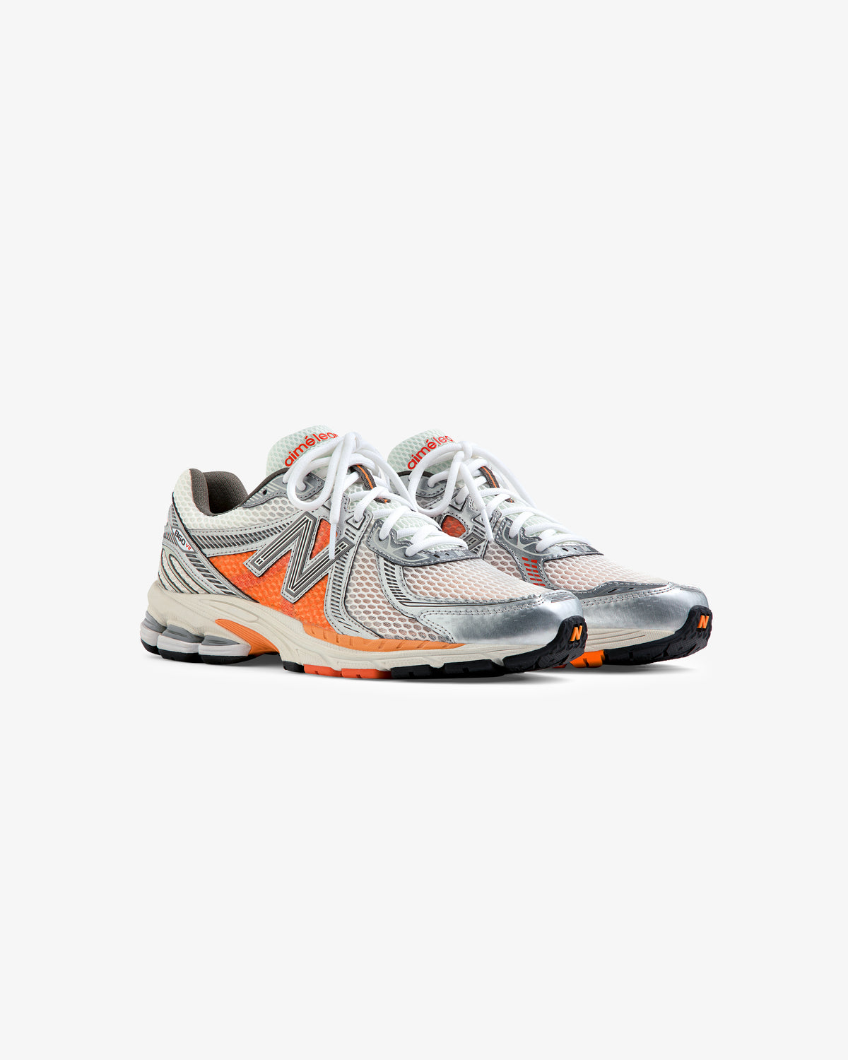 A pair of ALD / New Balance 860v2 gray and orange running shoes with white laces on a white background.