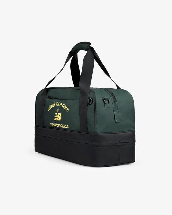 A dark green and black ALD / New Balance Travel Duffle Bag with yellow logo text on the side.