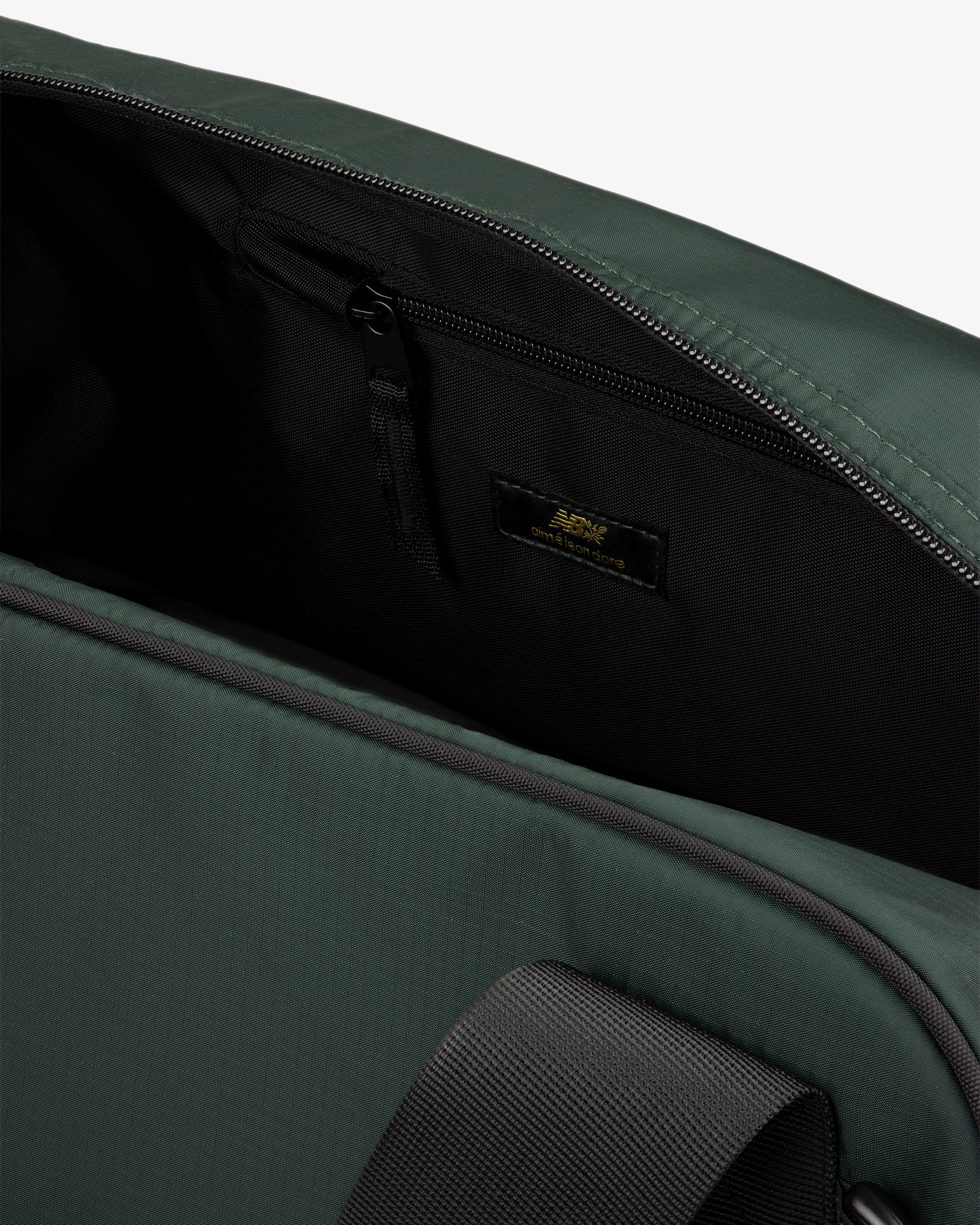 Close-up of ALD / New Balance Travel Duffle Bag open, showing black zippered inner pocket and inside label.