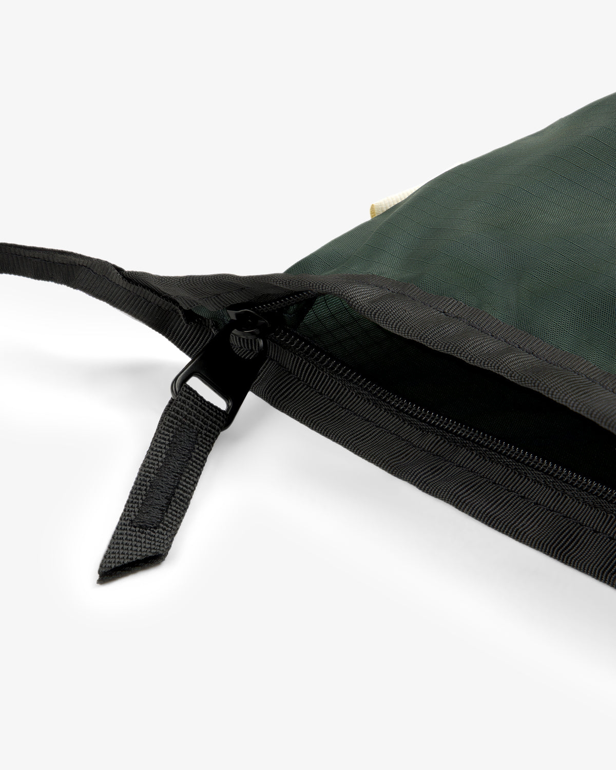 Close-up of a black zipper on the ALD / New Balance Nylon Sling Pouch in dark green, partially unzipped.