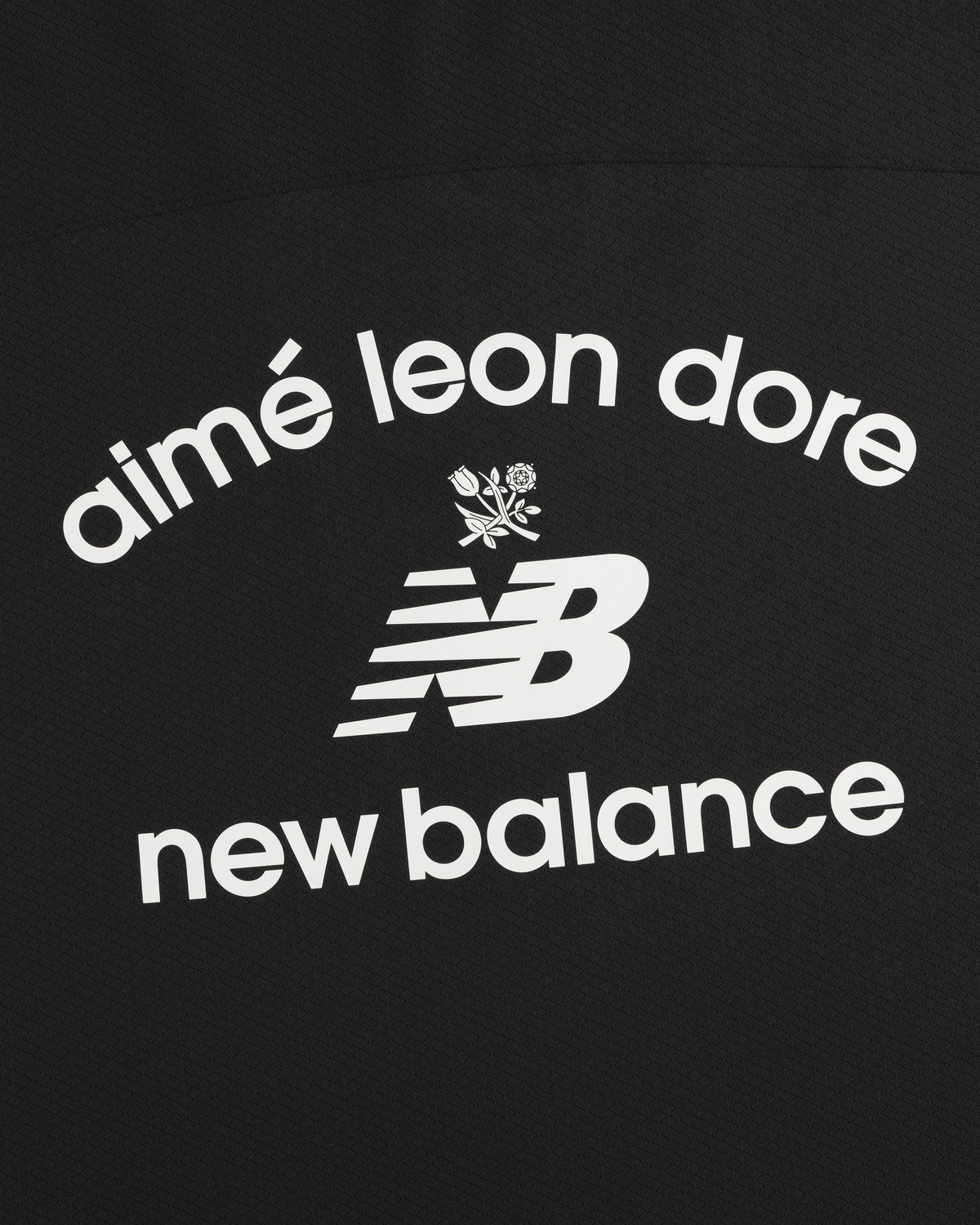 Black ALD / New Balance Full-Zip Warmup Hoodie with white arched text and small floral graphic on black fabric.