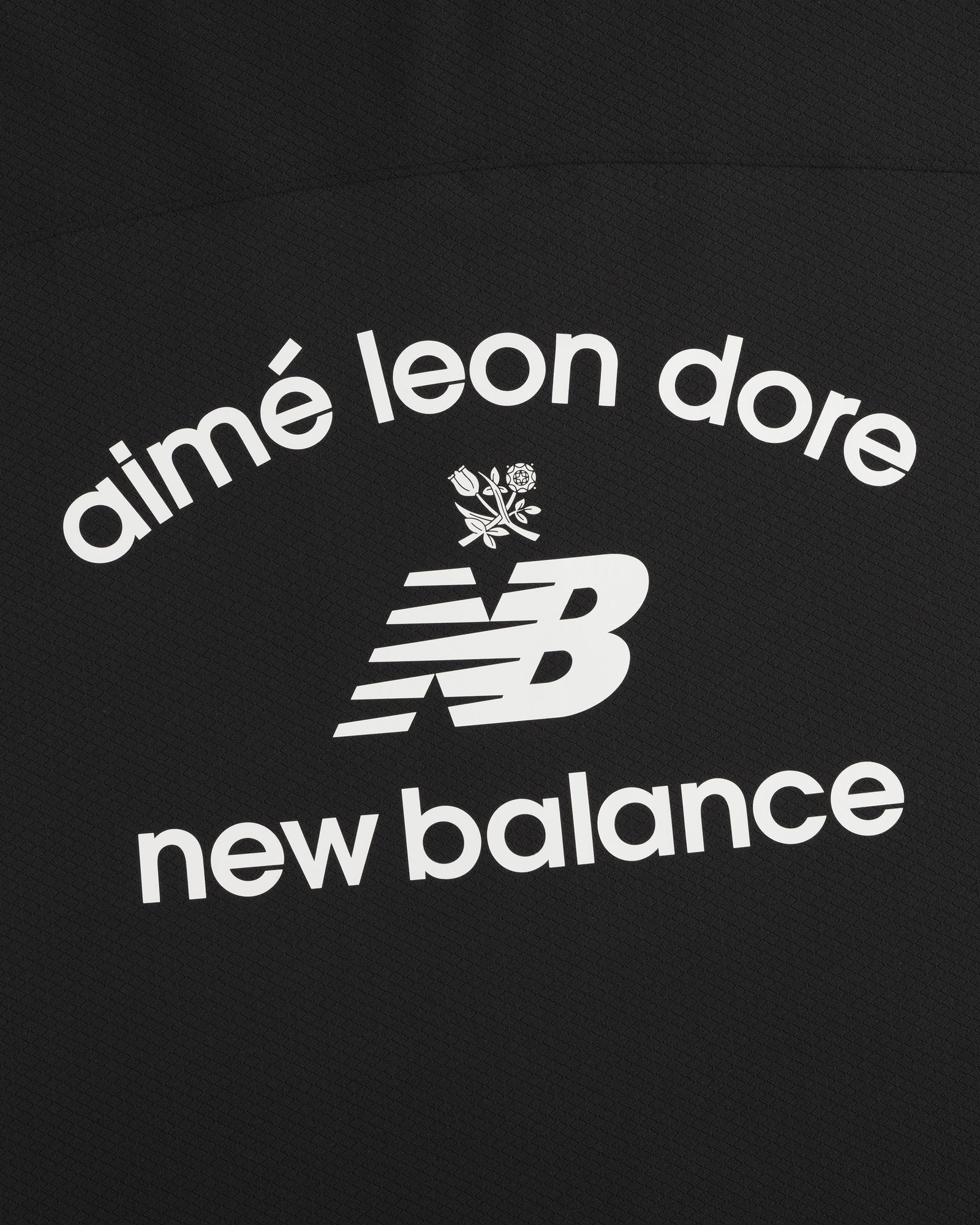 Black ALD / New Balance Full-Zip Warmup Hoodie with white arched text and small floral graphic on black fabric.