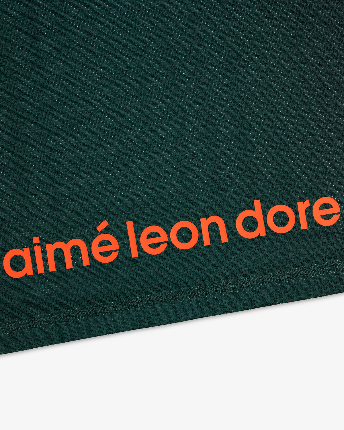 Close-up of dark green ALD / New Balance Running Gradient Singlet with bold orange aimé leon dore near the edge.