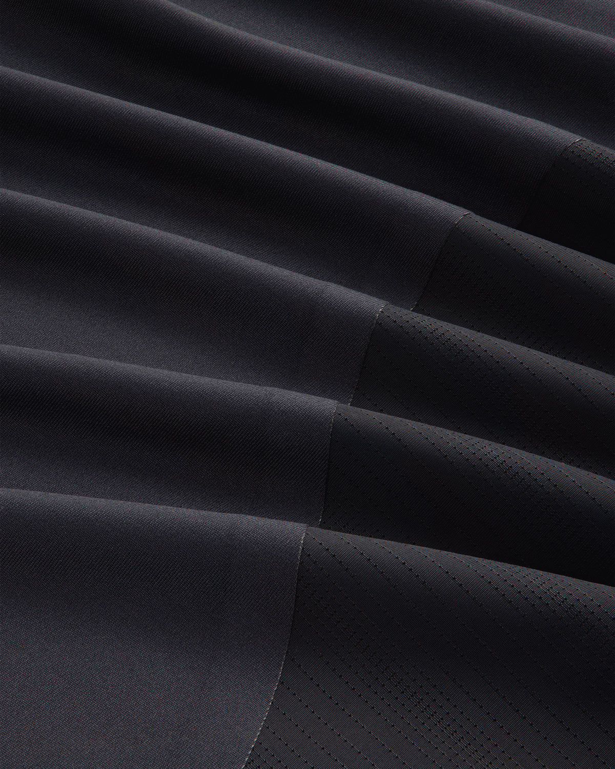 Close-up of the ALD / New Balance Performance Long-Sleeve Tee's dark, pleated fabric with matte and shiny textures.