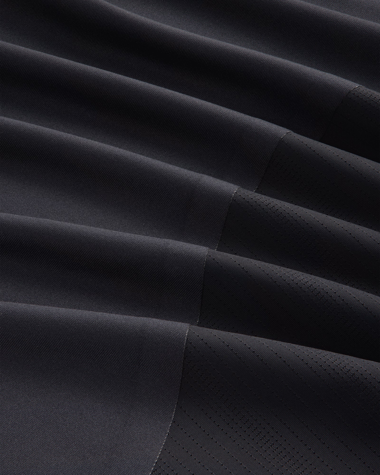Close-up of the ALD / New Balance Performance Long-Sleeve Tee's dark, pleated fabric with matte and shiny textures.