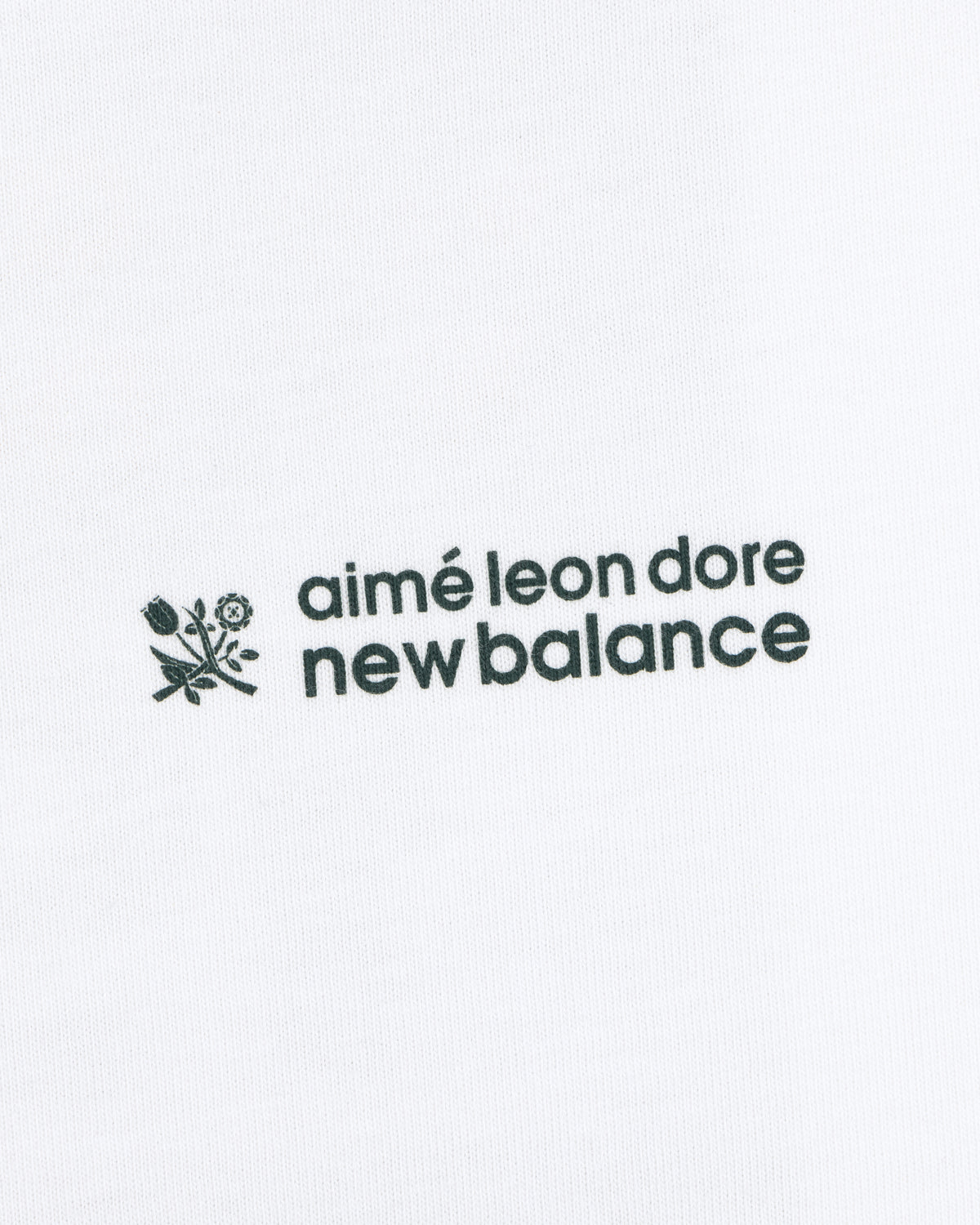 Black ALD / New Balance Running Bib Tee with logo and small flower graphic on white fabric background.