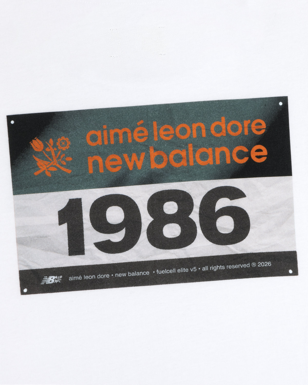 Rectangular label on white with "ALD / New Balance Running Bib Tee" and the number 1986.