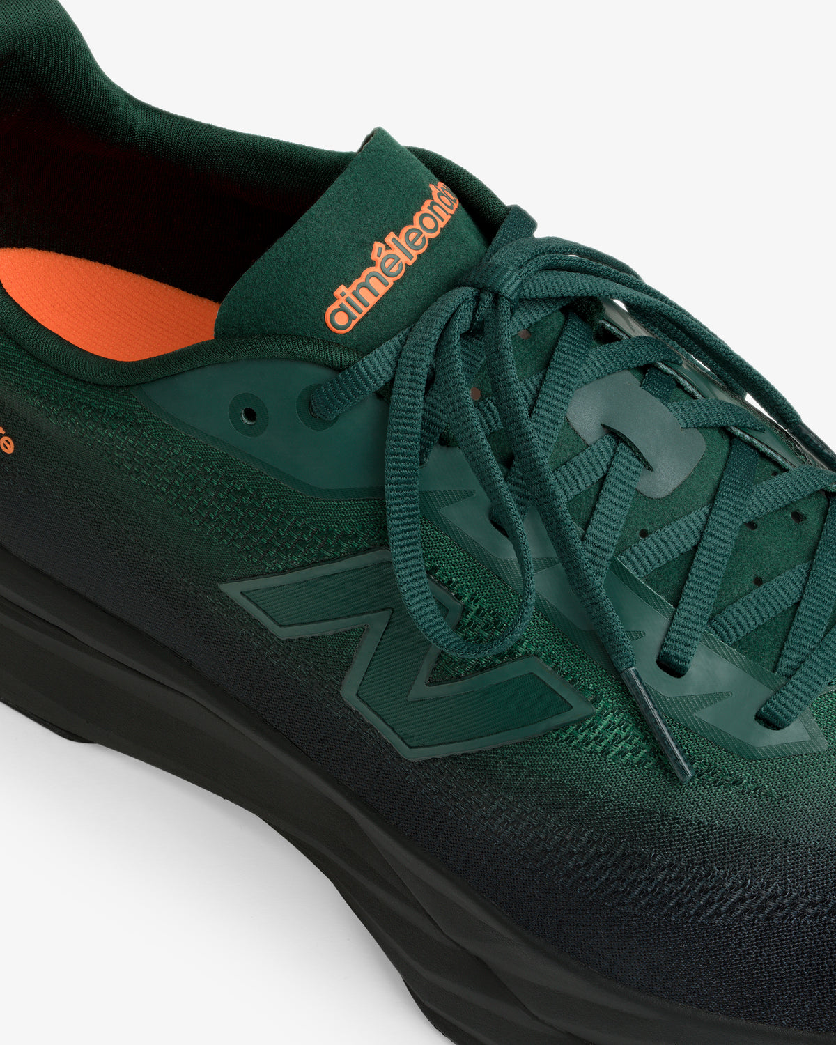 A dark green ALD / New Balance FuelCell SuperComp Elite v5 with orange branding on the tongue and orange lining.