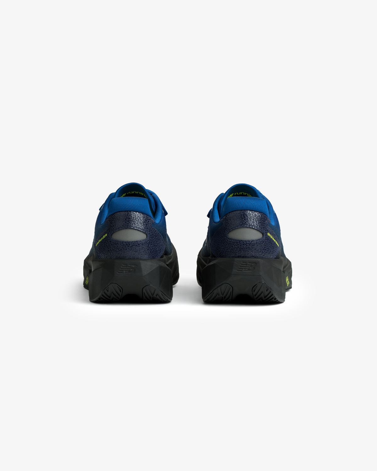 Rear view of ALD / New Balance FuelCell Rebel v5 in blue and black with textured soles on a white background.