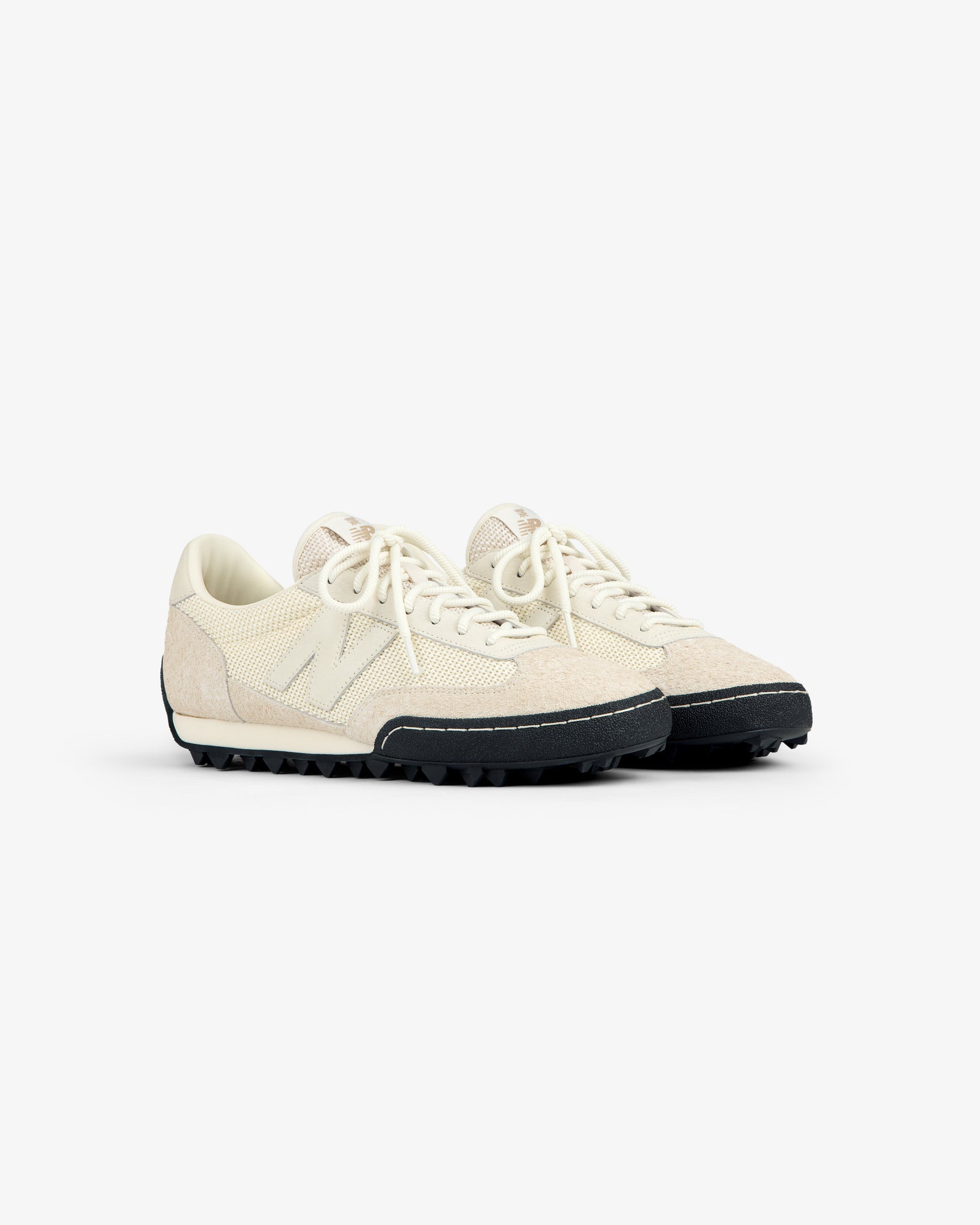 A pair of ALD / New Balance Gator off-white low-top sneakers with textured uppers and black rubber soles.