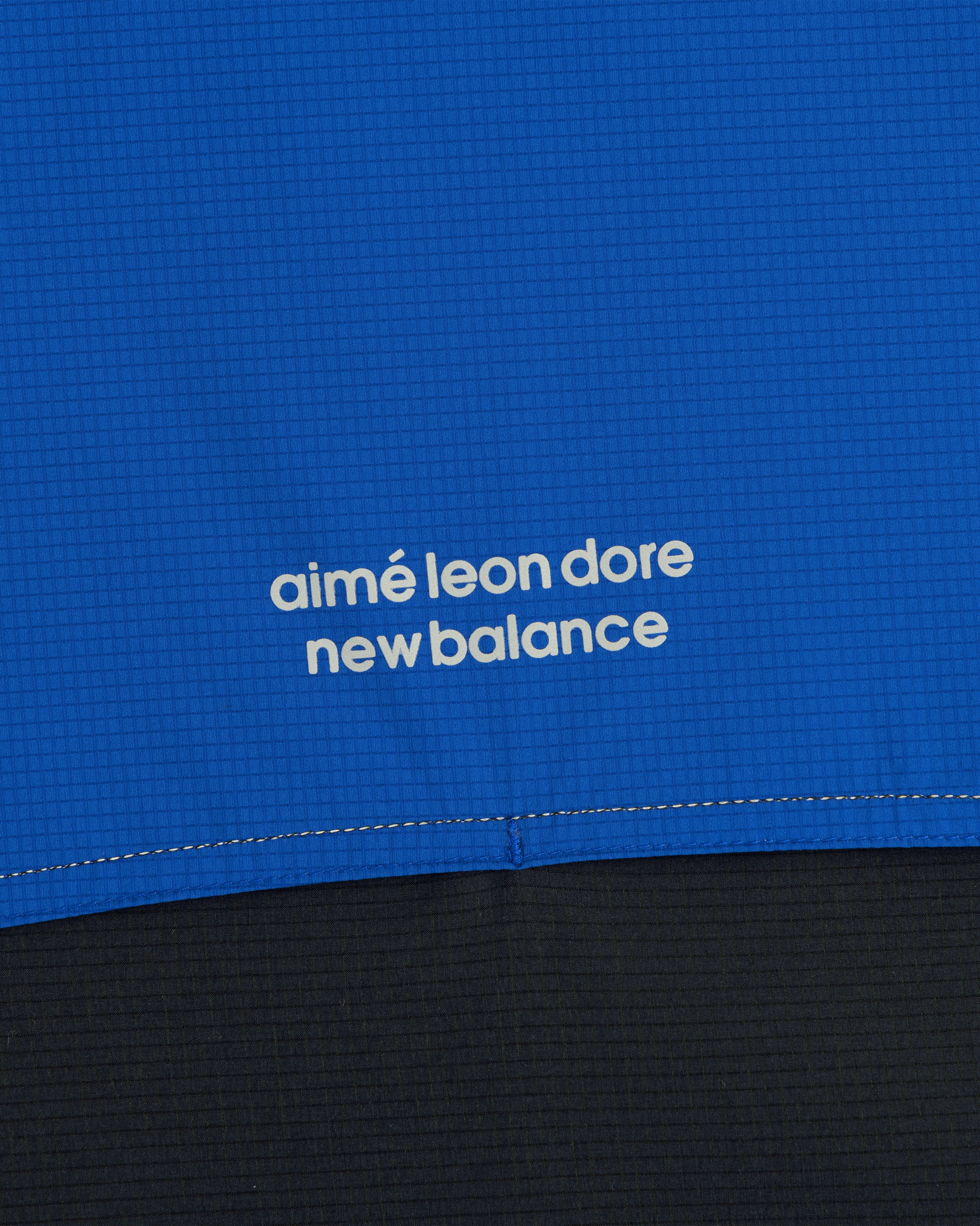 Close-up of blue ALD / New Balance Performance Nylon Jacket with white logo in lowercase letters.