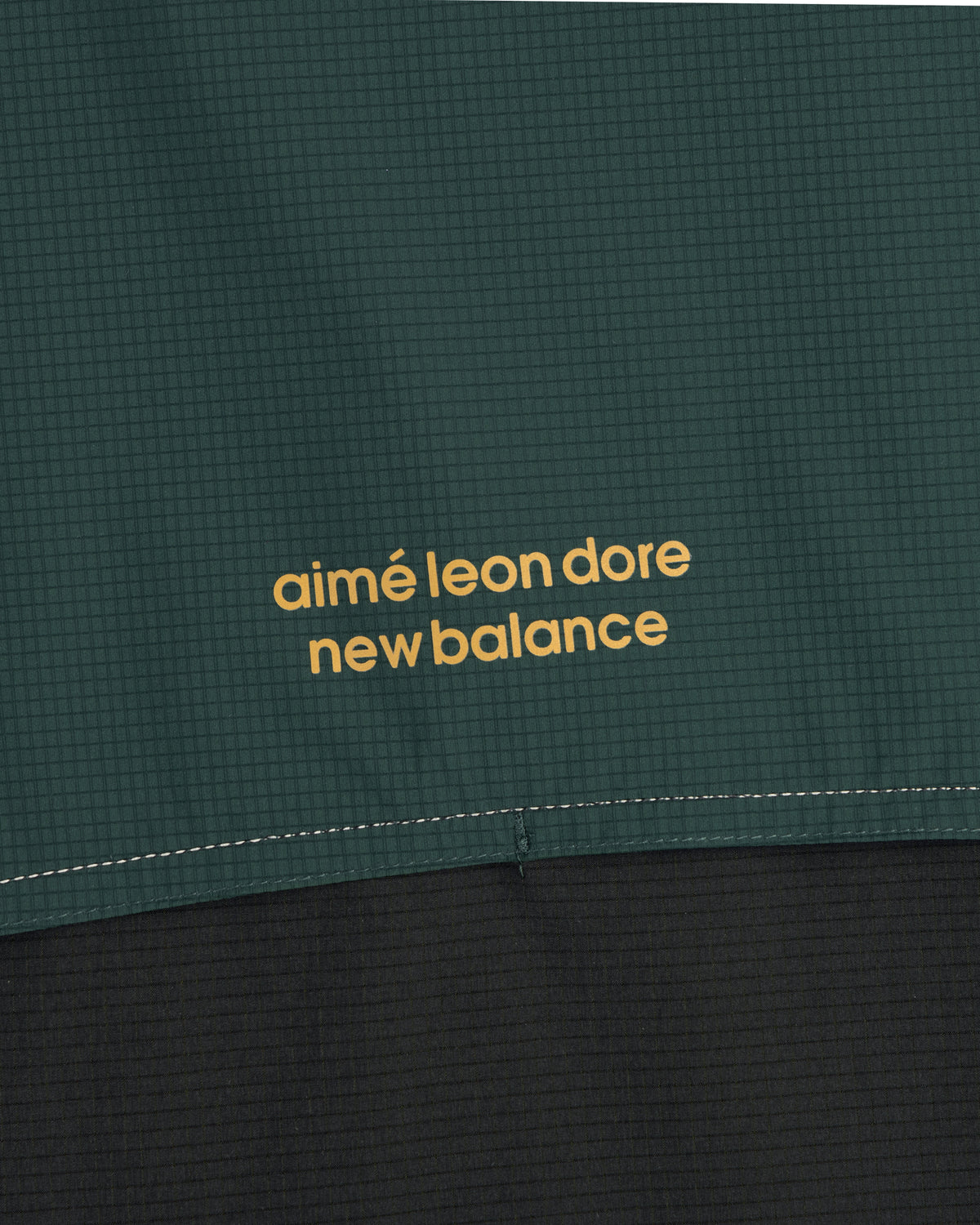 Close-up of the ALD / New Balance Performance Nylon Jacket in green and black with yellow branding.