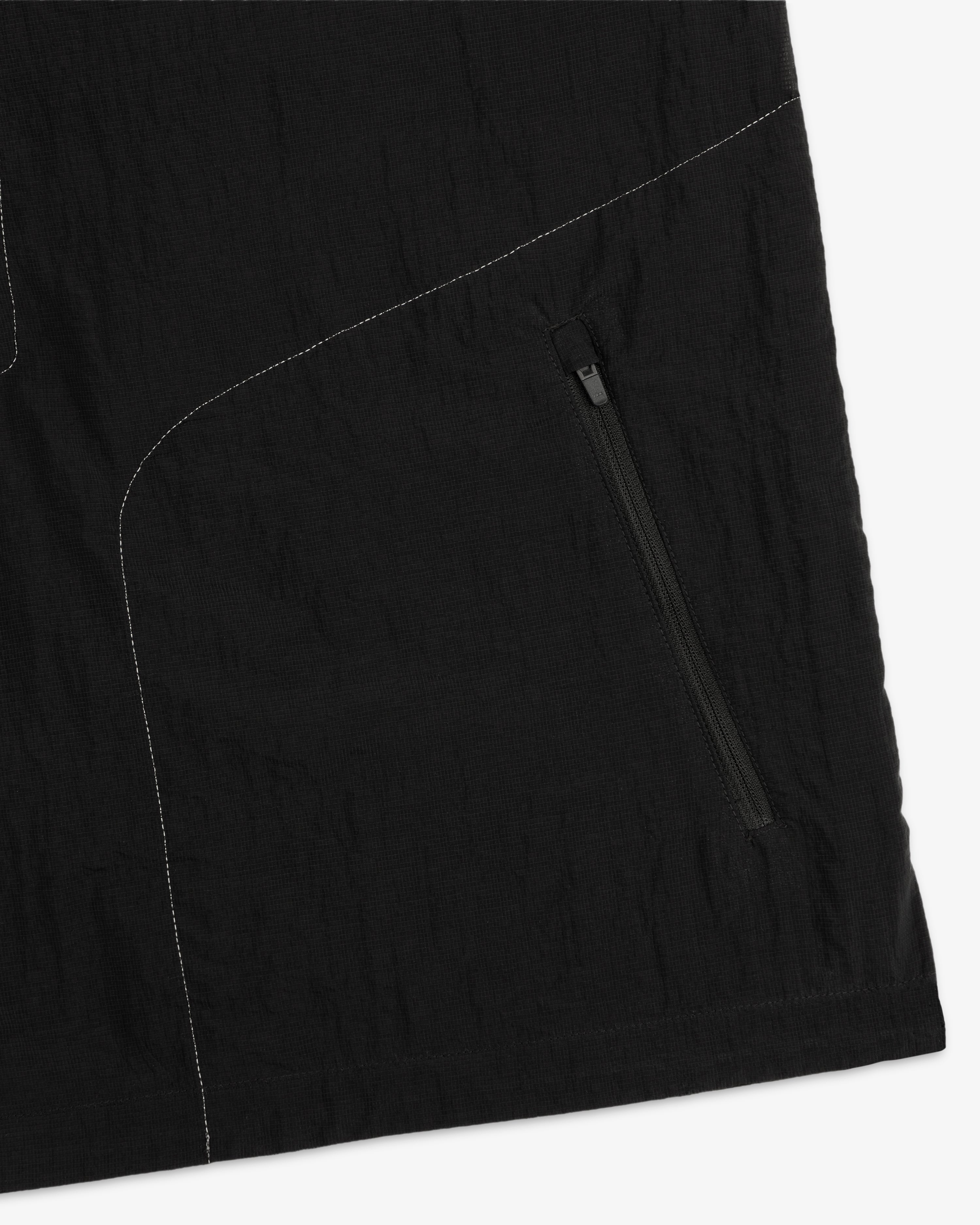Close-up of the ALD / New Balance Breathable Half-Zip Pullover in black with white stitching and diagonal zip pocket.