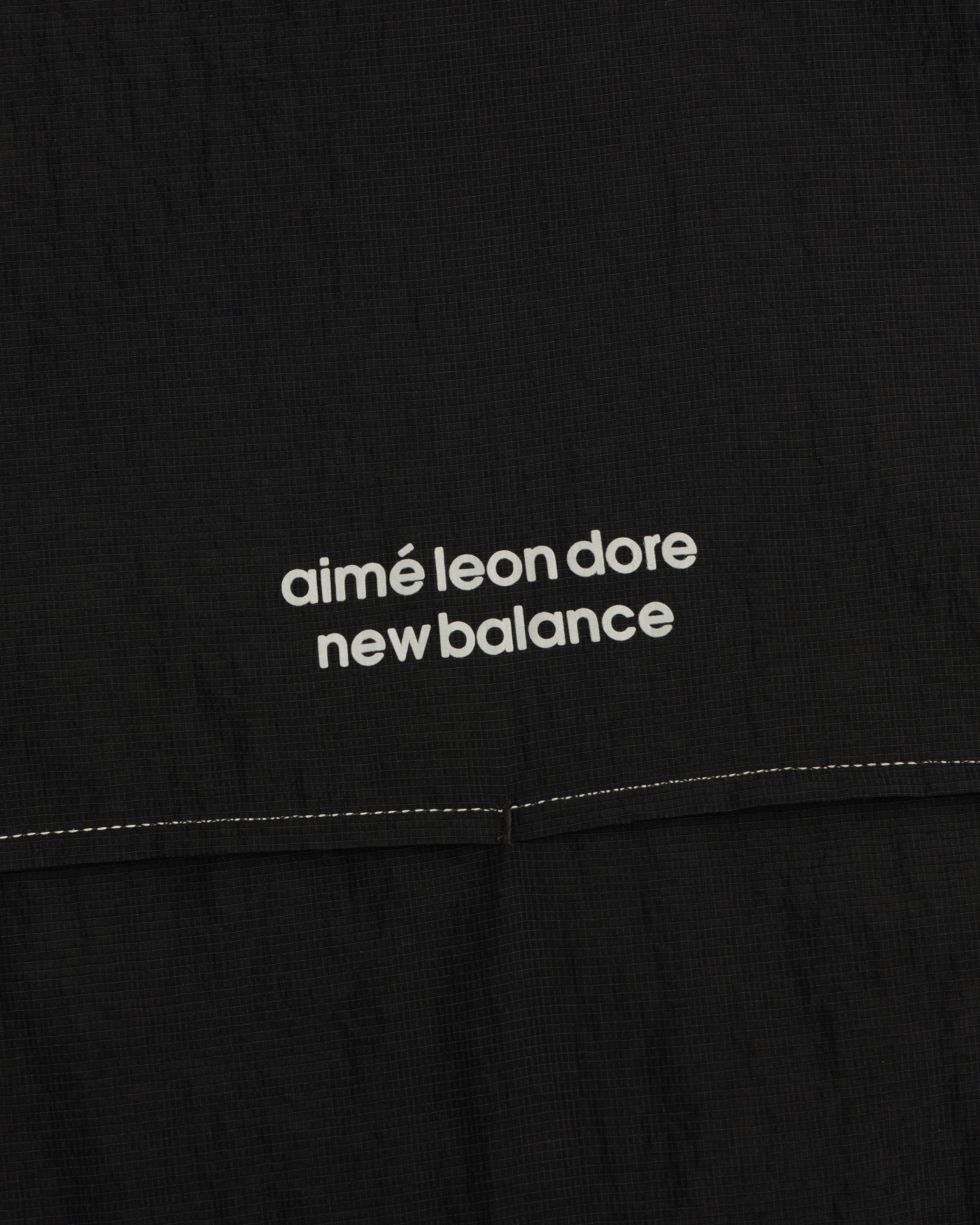 Close-up of black ALD / New Balance Breathable Half-Zip Pullover with white logo above a stitched seam.