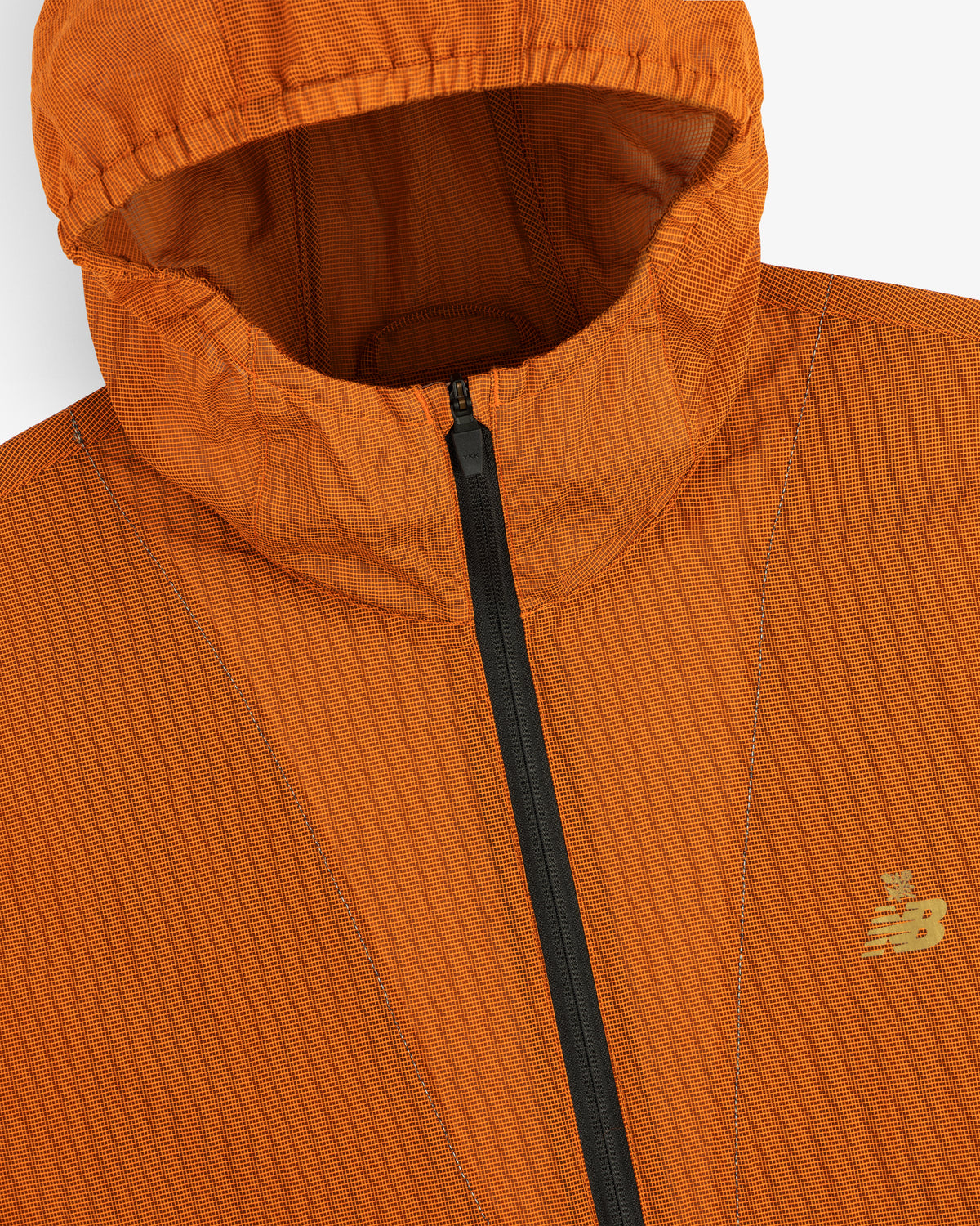 Close-up of the ALD / New Balance Breathable Half-Zip Pullover in orange with black zipper and yellow chest logo.