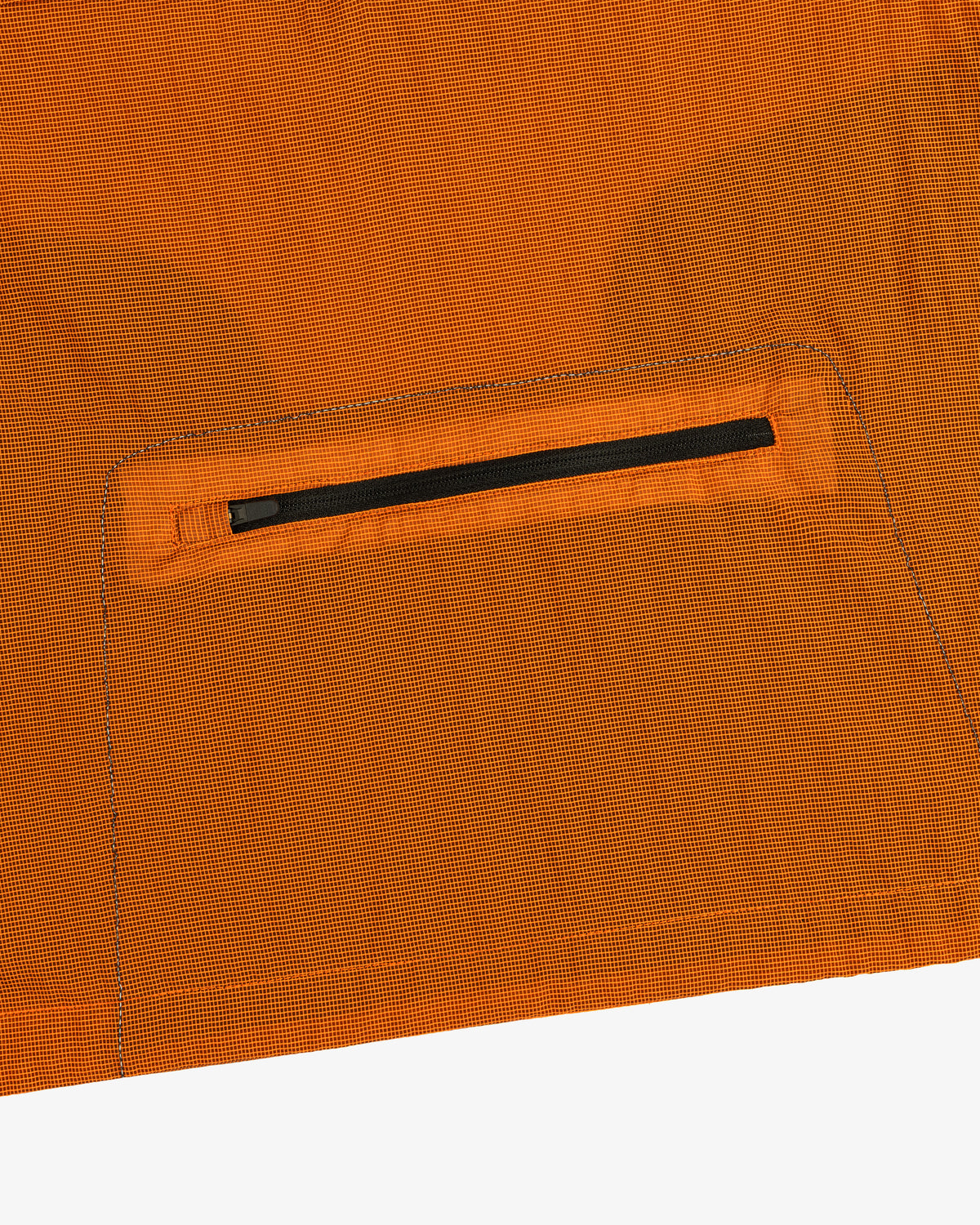Close-up of the ALD / New Balance Breathable Half-Zip Pullover’s orange fabric with a small black zipper pocket.