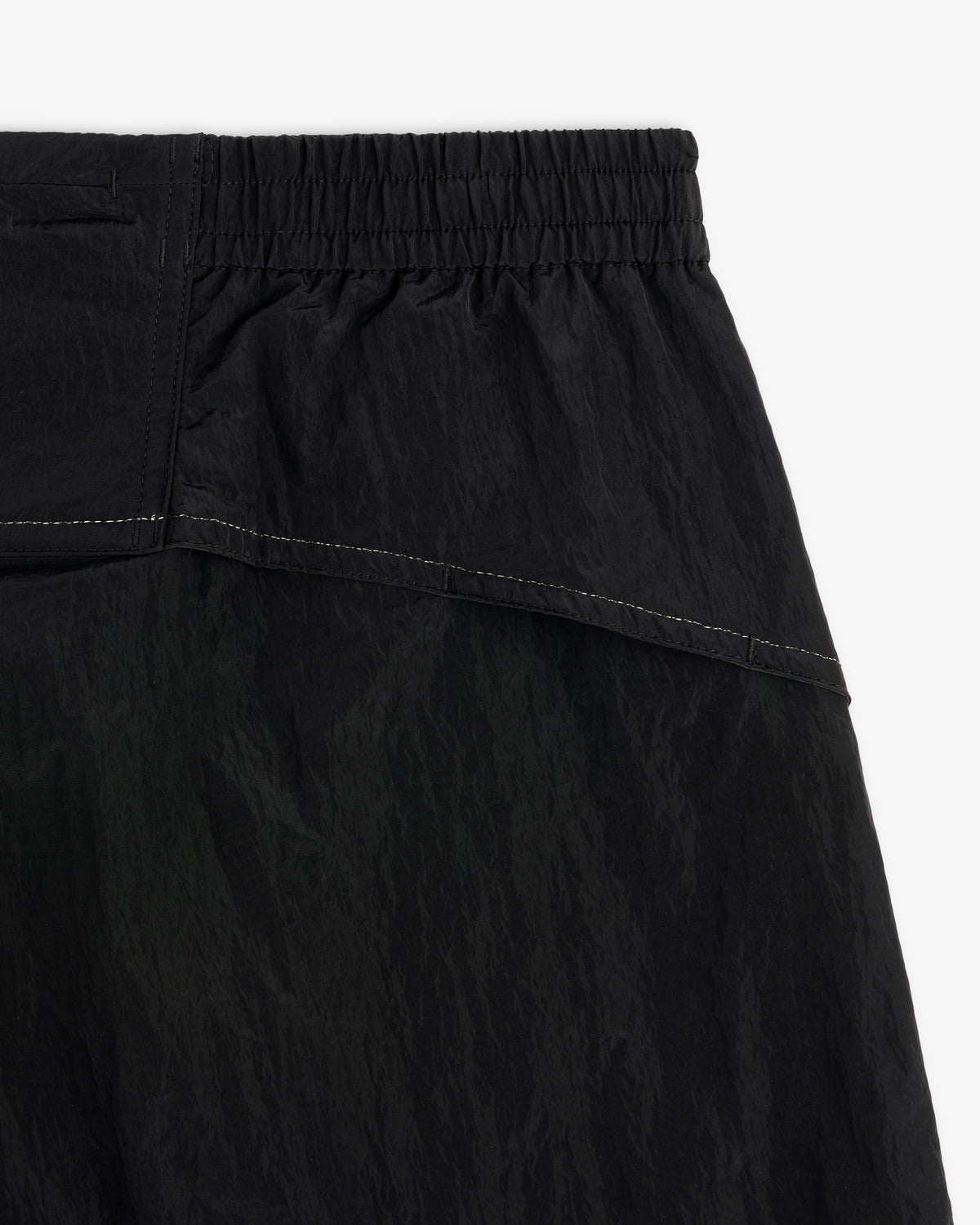 Close-up of ALD / New Balance Lightweight Nylon Warmup Pant with elastic waistband, textured fabric, and white stitching.