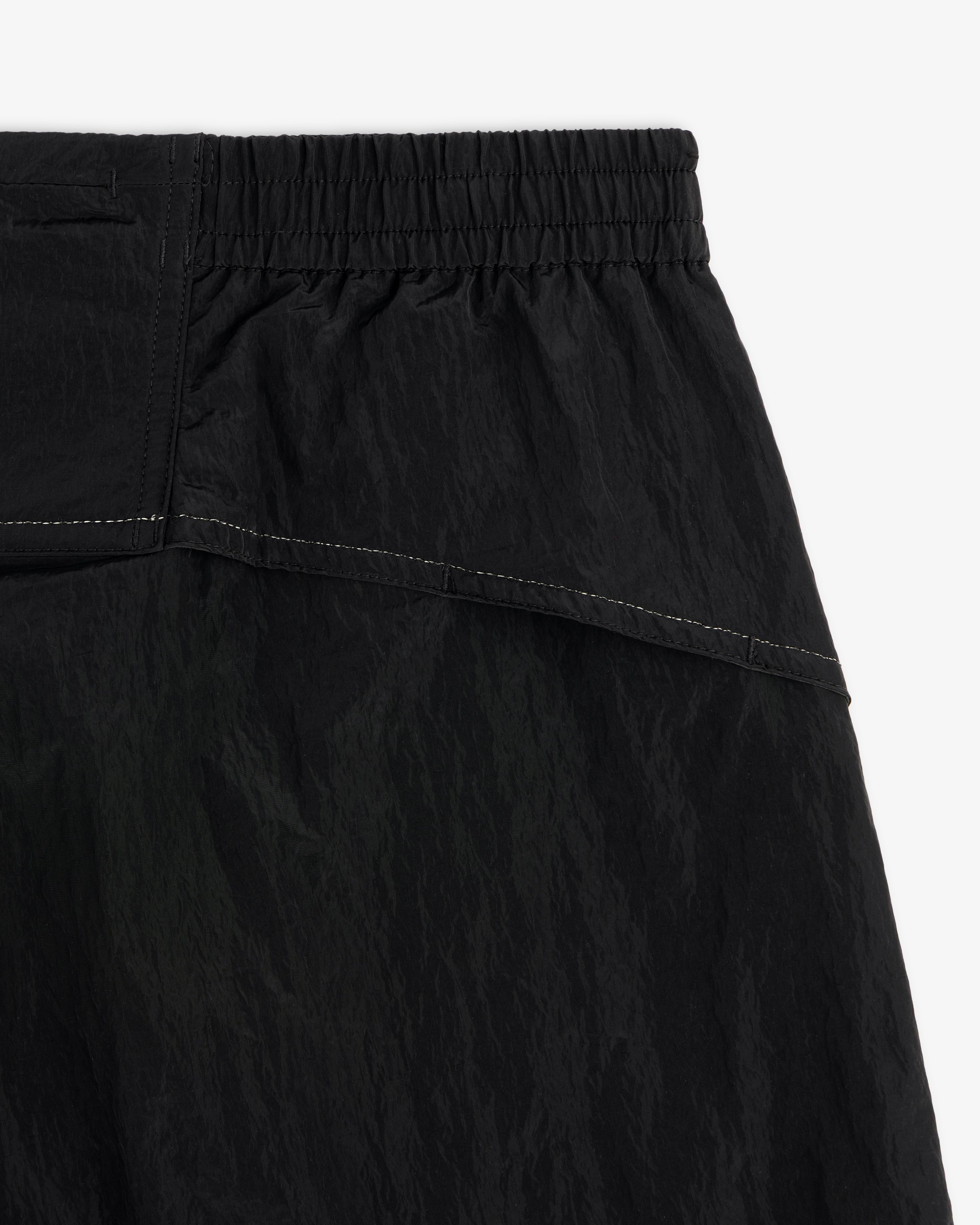 Close-up of ALD / New Balance Lightweight Nylon Warmup Pant with elastic waistband, textured fabric, and white stitching.
