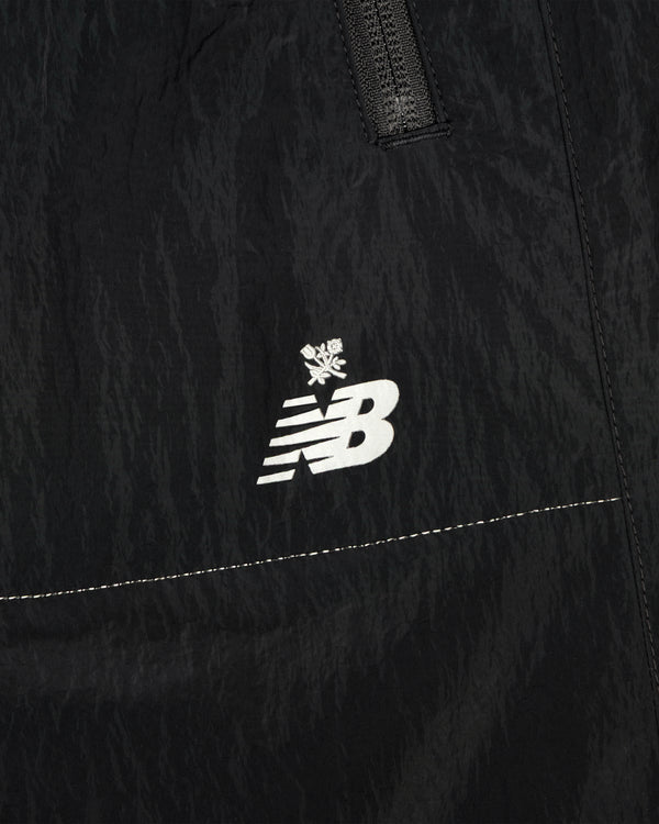 Close-up of black ALD / New Balance Lightweight Nylon Warmup Pant with white logo and small snowflake above it.