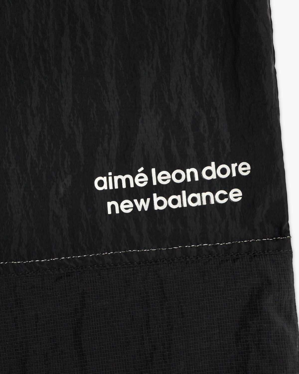 Black nylon ALD / New Balance Lightweight Warmup Pant with white branding and visible stitching at the hem.