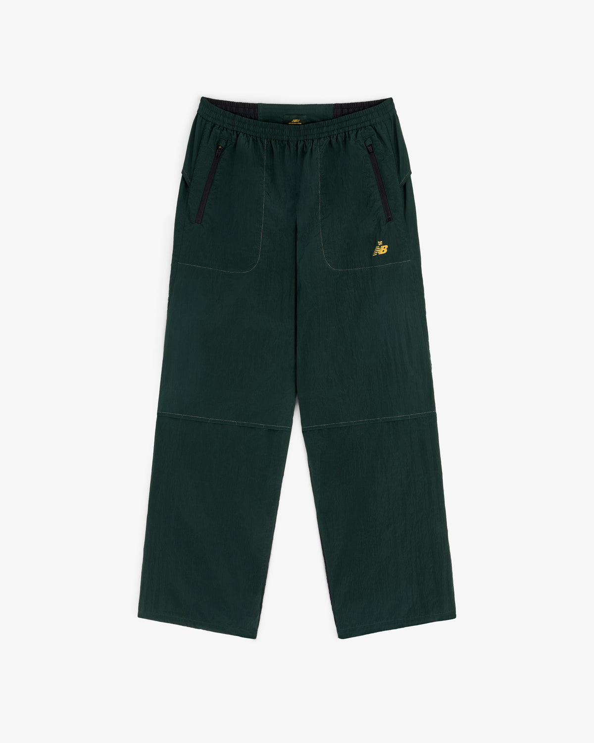 ALD / New Balance Lightweight Nylon Warmup Pant in dark green with front pockets, black zippers, and yellow NB logo.