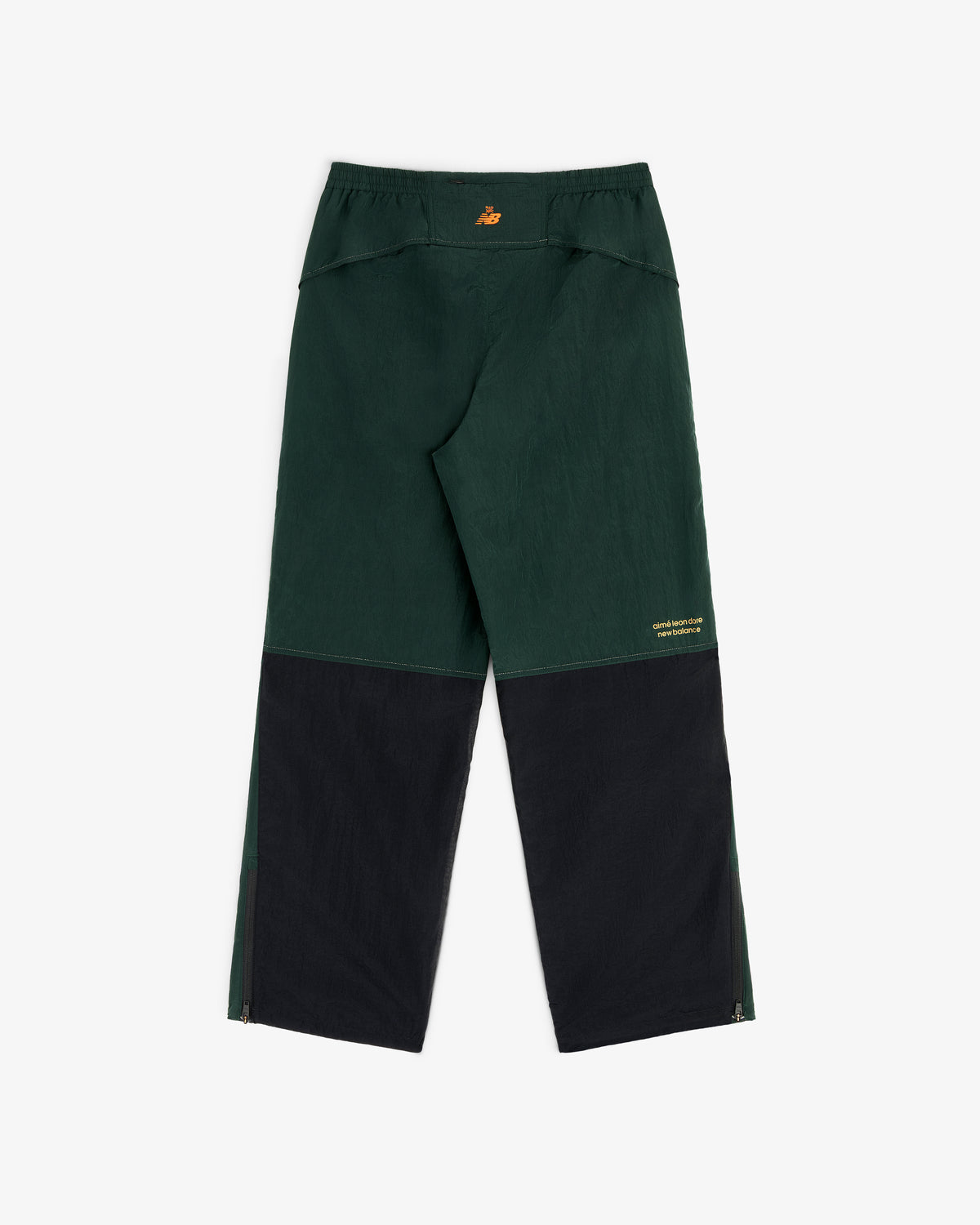 ALD/New Balance warmup pants in dark green/black with yellow logo on waistband and leg, loose fit, lightweight nylon.