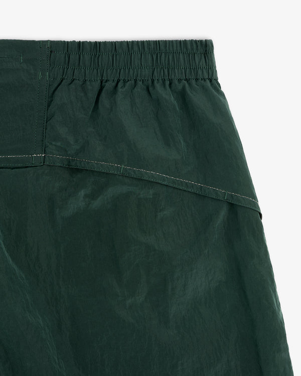 Close-up of ALD / New Balance Lightweight Nylon Warmup Pant in forest green with elastic waistband and visible stitching.