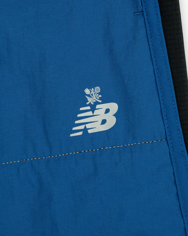 Close-up of blue ALD / New Balance Performance Lightweight Running Short with white logo and two crossed roses above it.