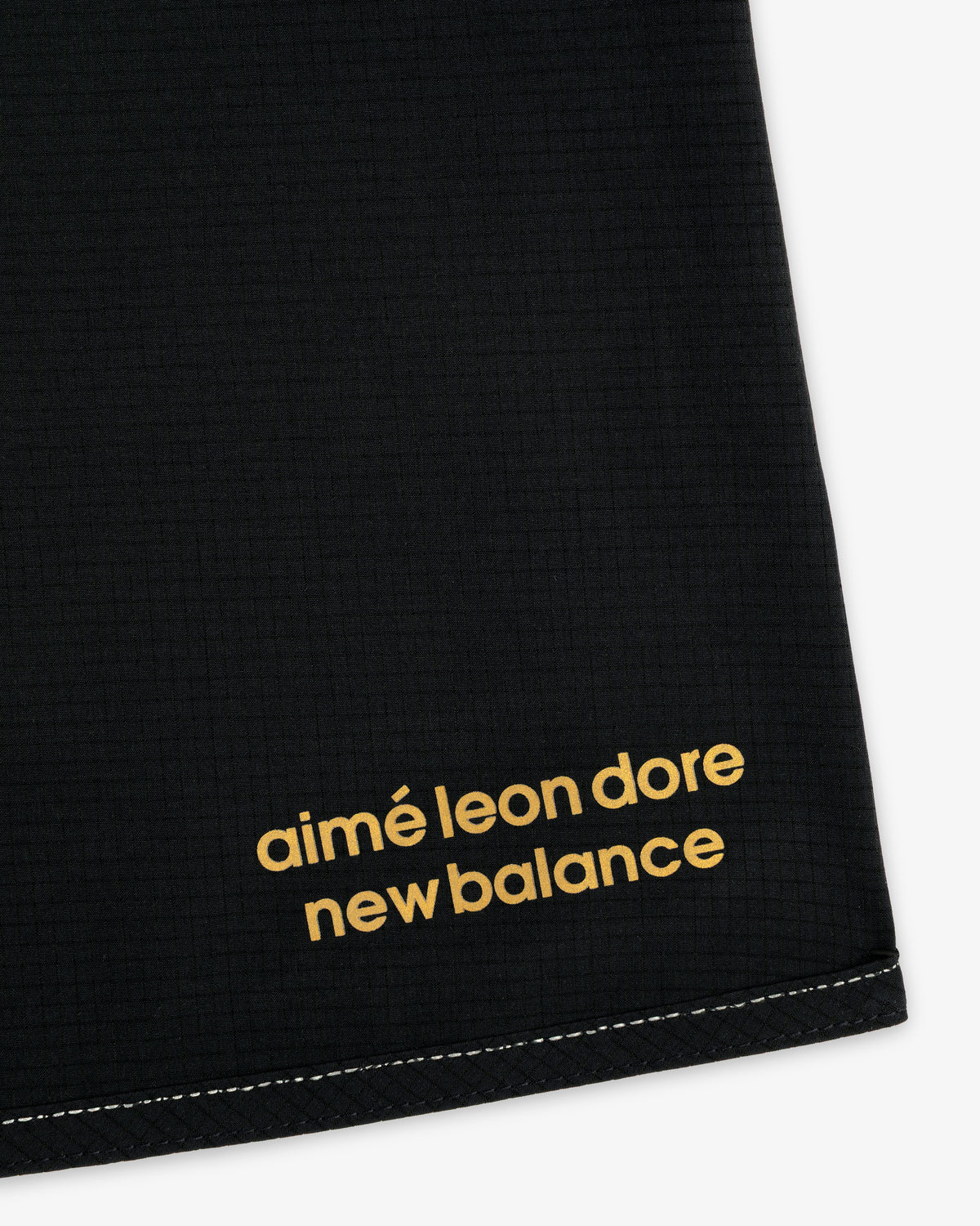 Close-up of black ALD / New Balance Performance Lightweight Running Short with yellow logo in the corner.
