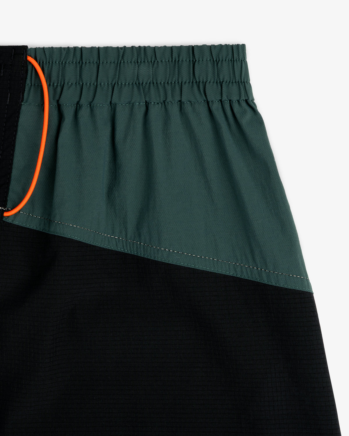 Close-up of ALD / New Balance Performance Lightweight Running Short in green and black with elastic waist and orange drawstring.