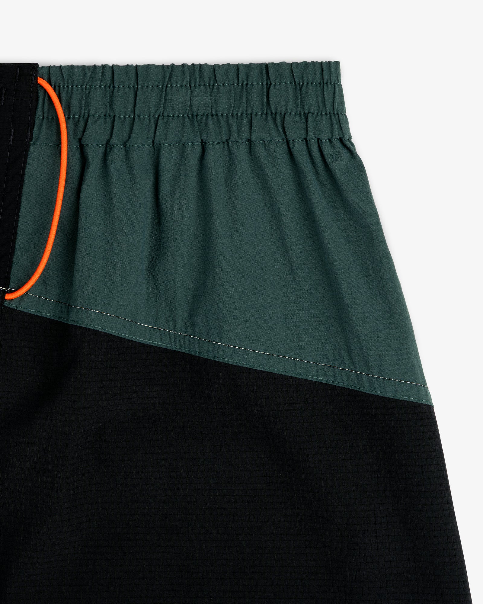 Close-up of ALD / New Balance Performance Lightweight Running Short in green and black with elastic waist and orange drawstring.