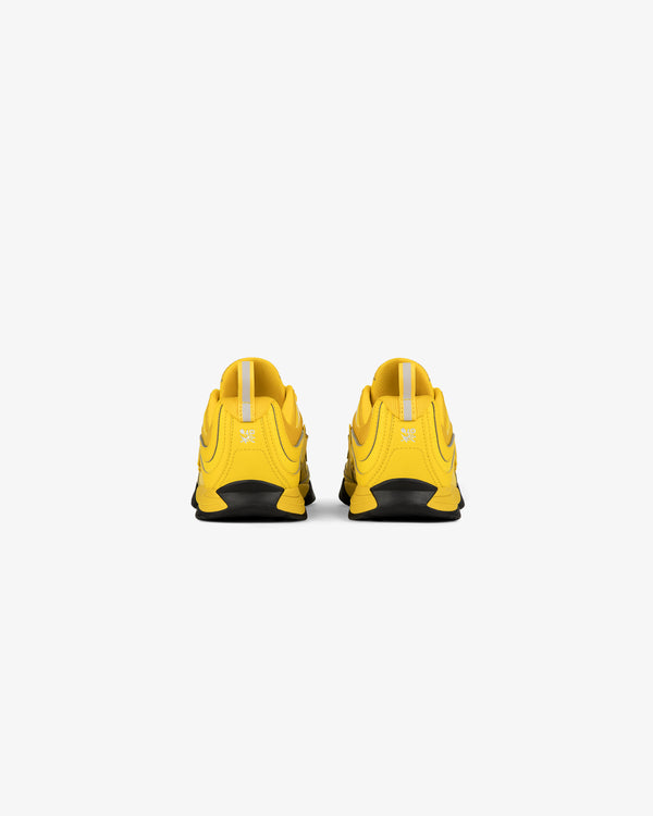 Back view of ALD / New Balance RC56 yellow athletic shoes with black soles on a white background.
