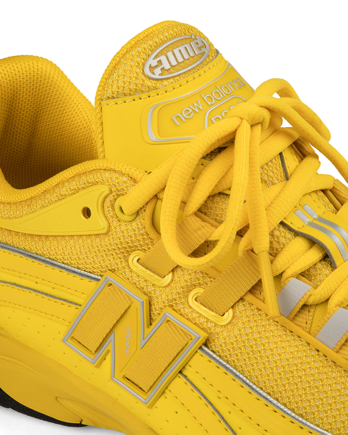 Close-up of a bright yellow ALD / New Balance RC56 sneaker with laces, mesh texture, and the N logo on the side.