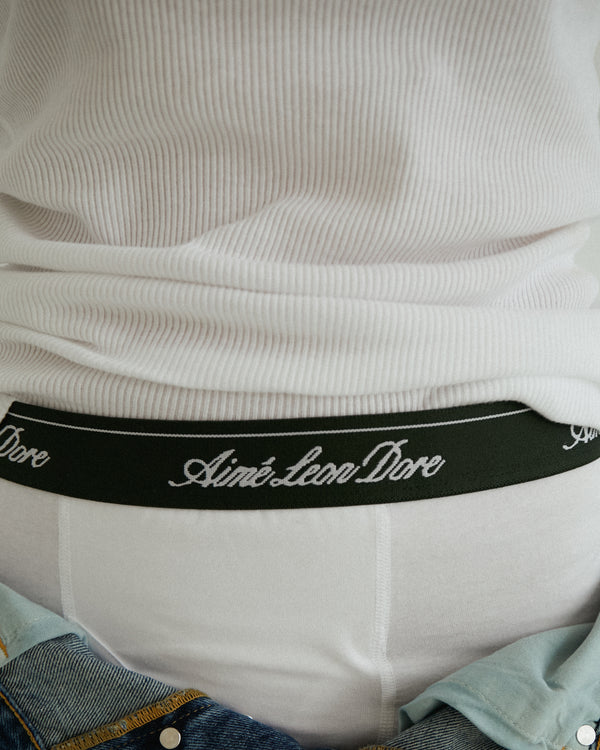 Close-up of a person wearing a white ribbed shirt and Boxer Brief 3-Pack with Aimé Leon Dore on the waistband.