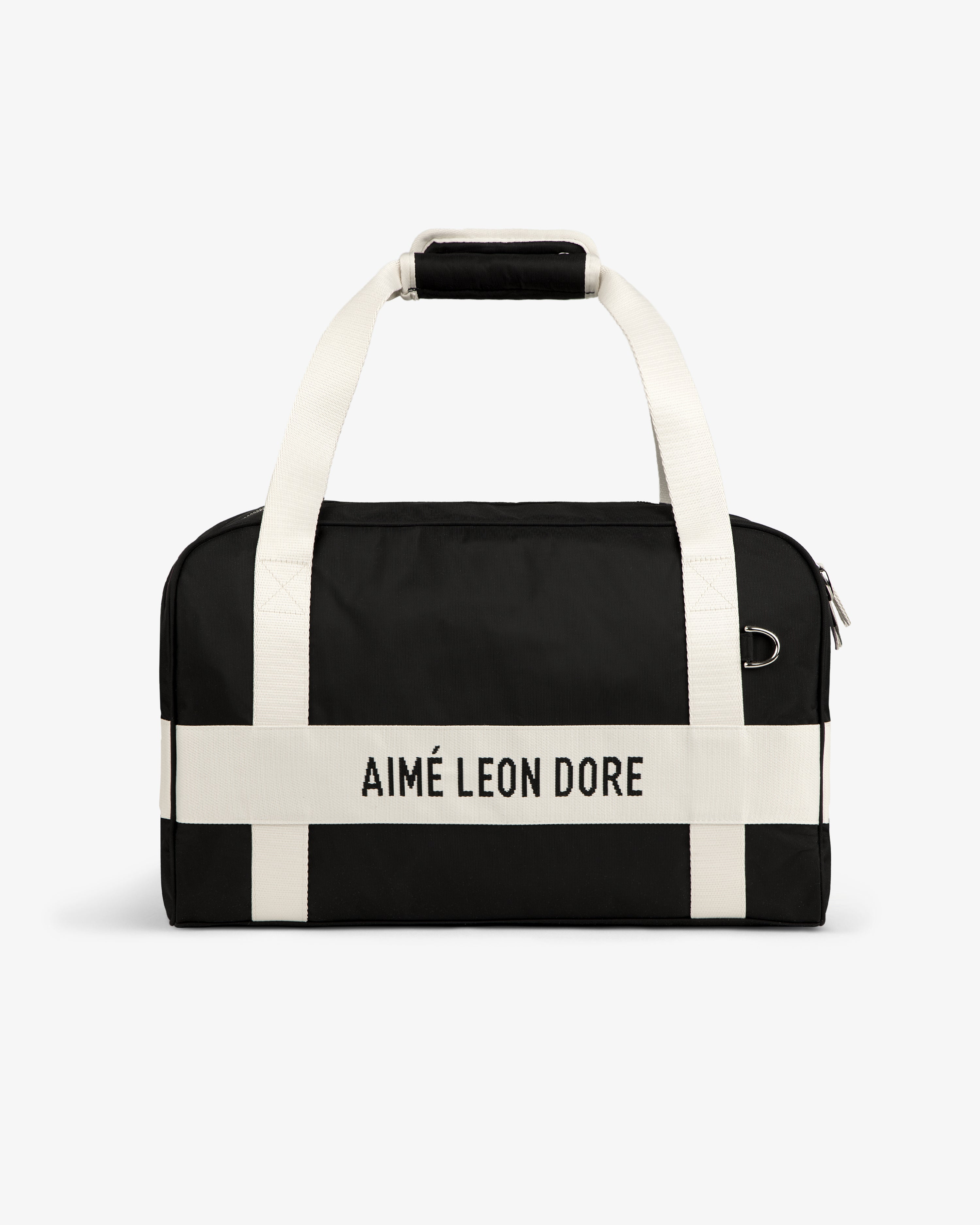 Nylon Duffle Bag with white handles and AIMÉ LEON DORE white strap, shown against a white background.