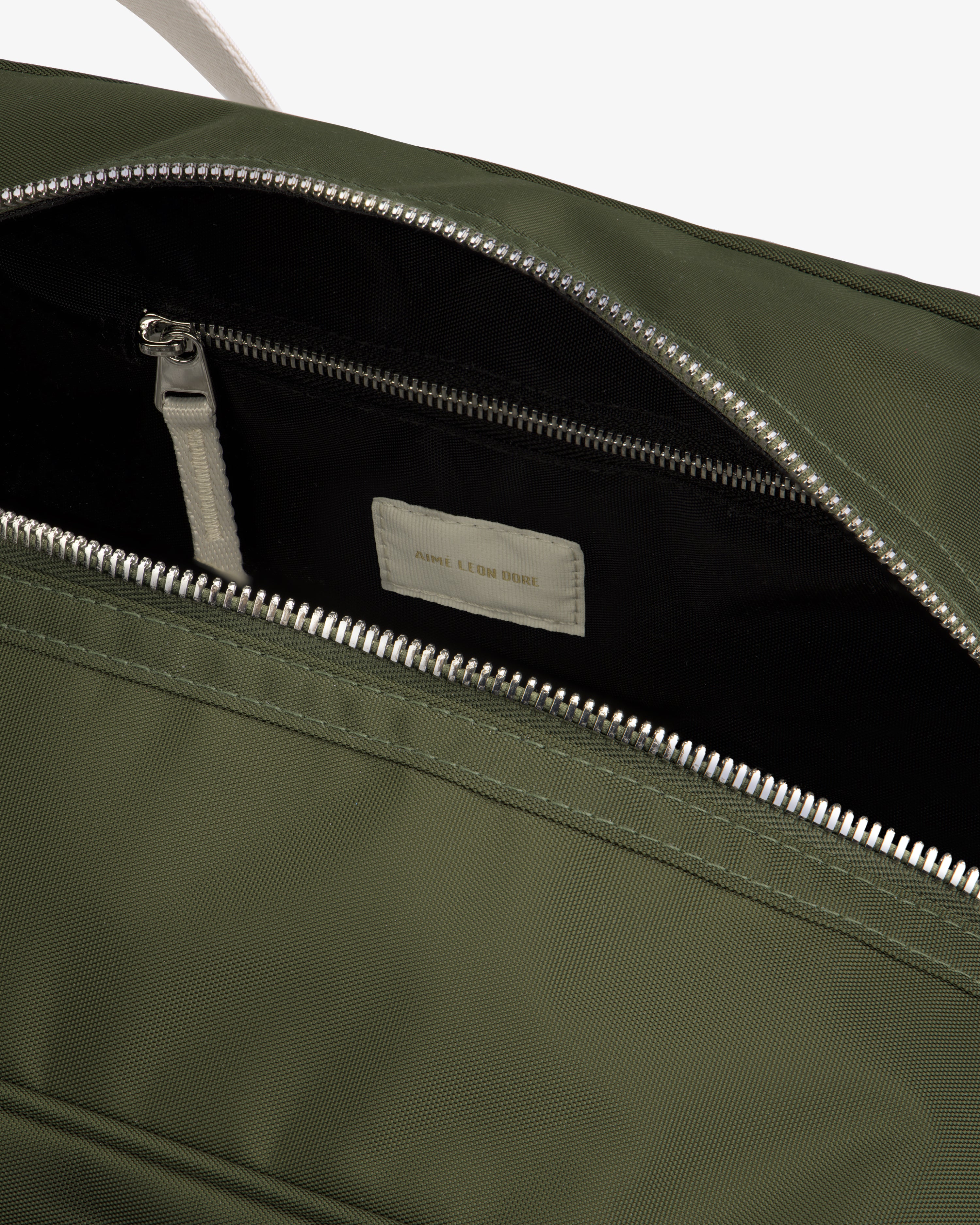 Close-up of an open Nylon Duffle Bag in olive green with a silver zipper, showing interior zip pocket and label.