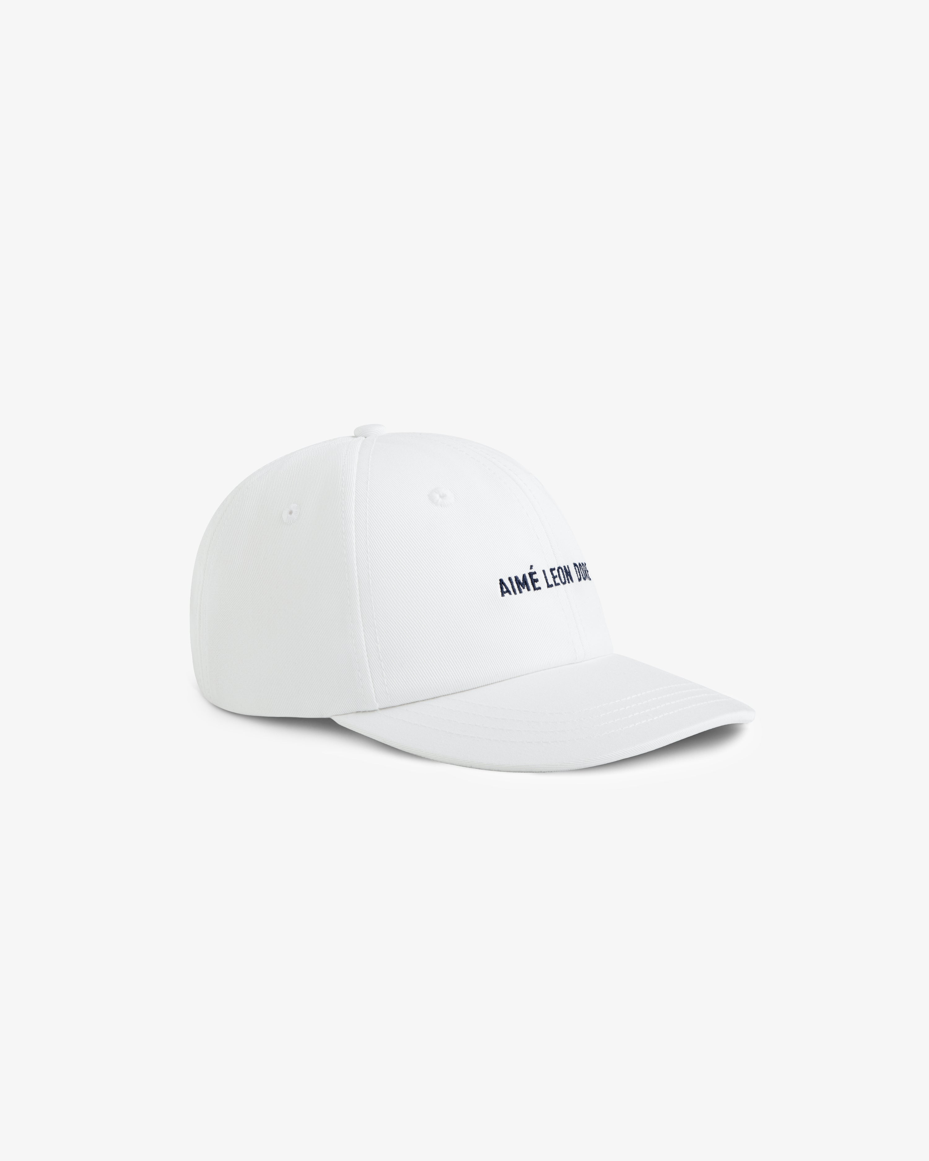 Core Logo Hat in white with small black AIMÉ LEON DORE text on the front, shown at an angle on a white background.
