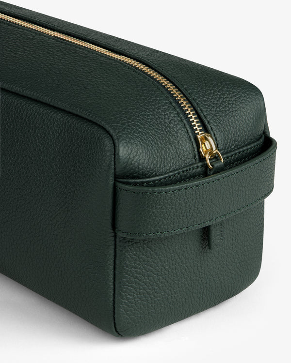 A close-up of the Leather Traveler Kit—a dark green leather bag with a gold zipper and side handle.