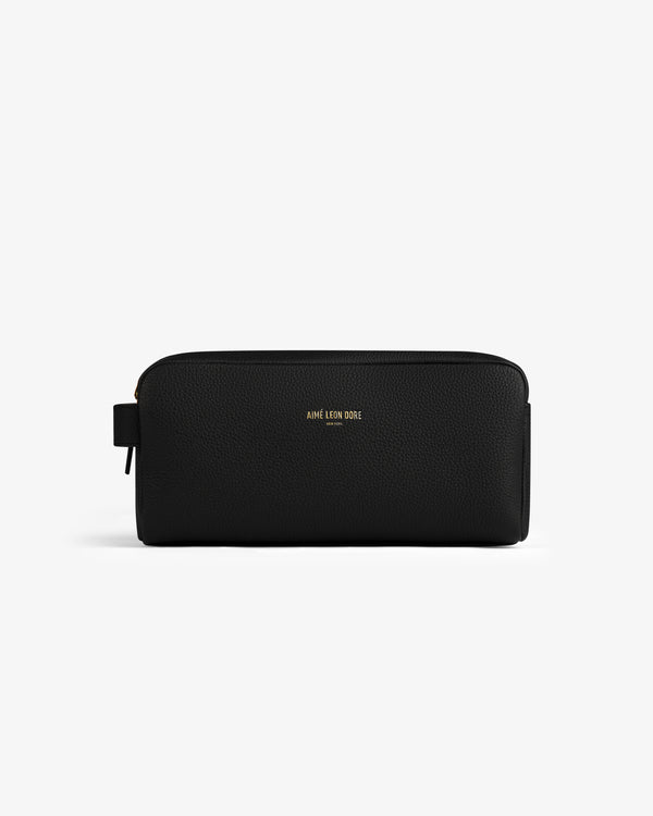 The Leather Traveler Kit is a black leather zippered toiletry bag with a side handle and gold AIMÉ LEON DORE branding.