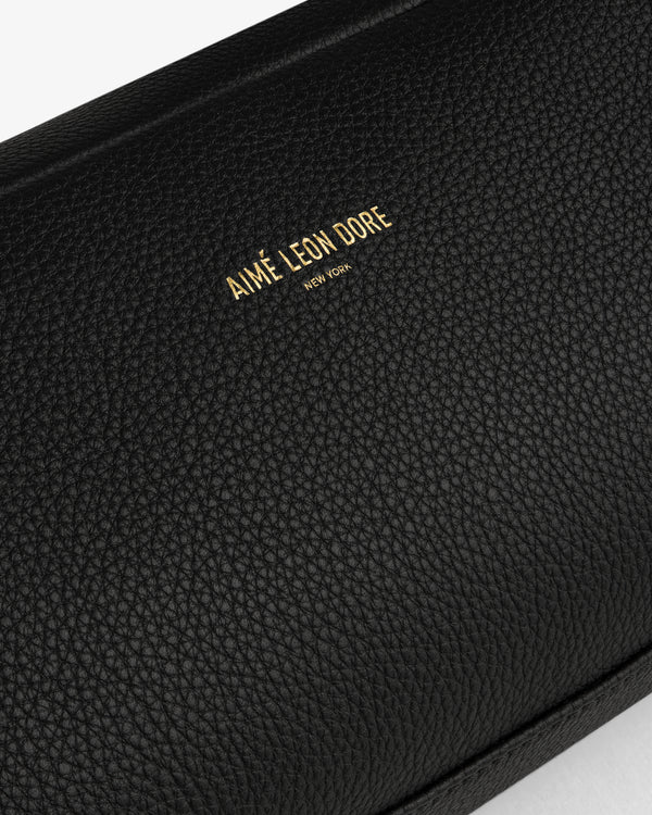 Close-up of the Leather Traveler Kit in black textured leather with AIMÉ LEON DORE NEW YORK embossed in gold.