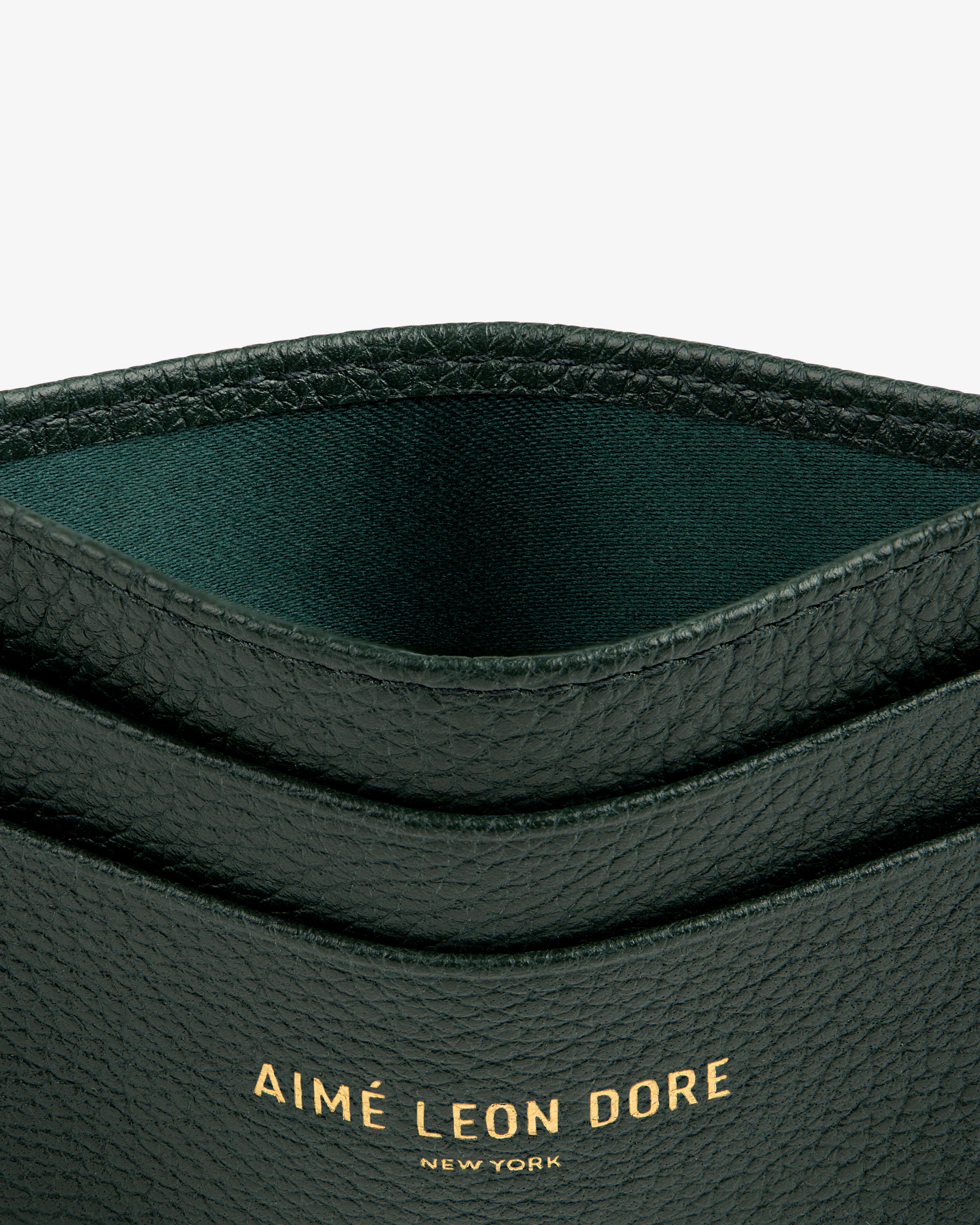 Close-up of a textured black Leather Card Holder with AIMÉ LEON DORE NEW YORK embossed in gold.