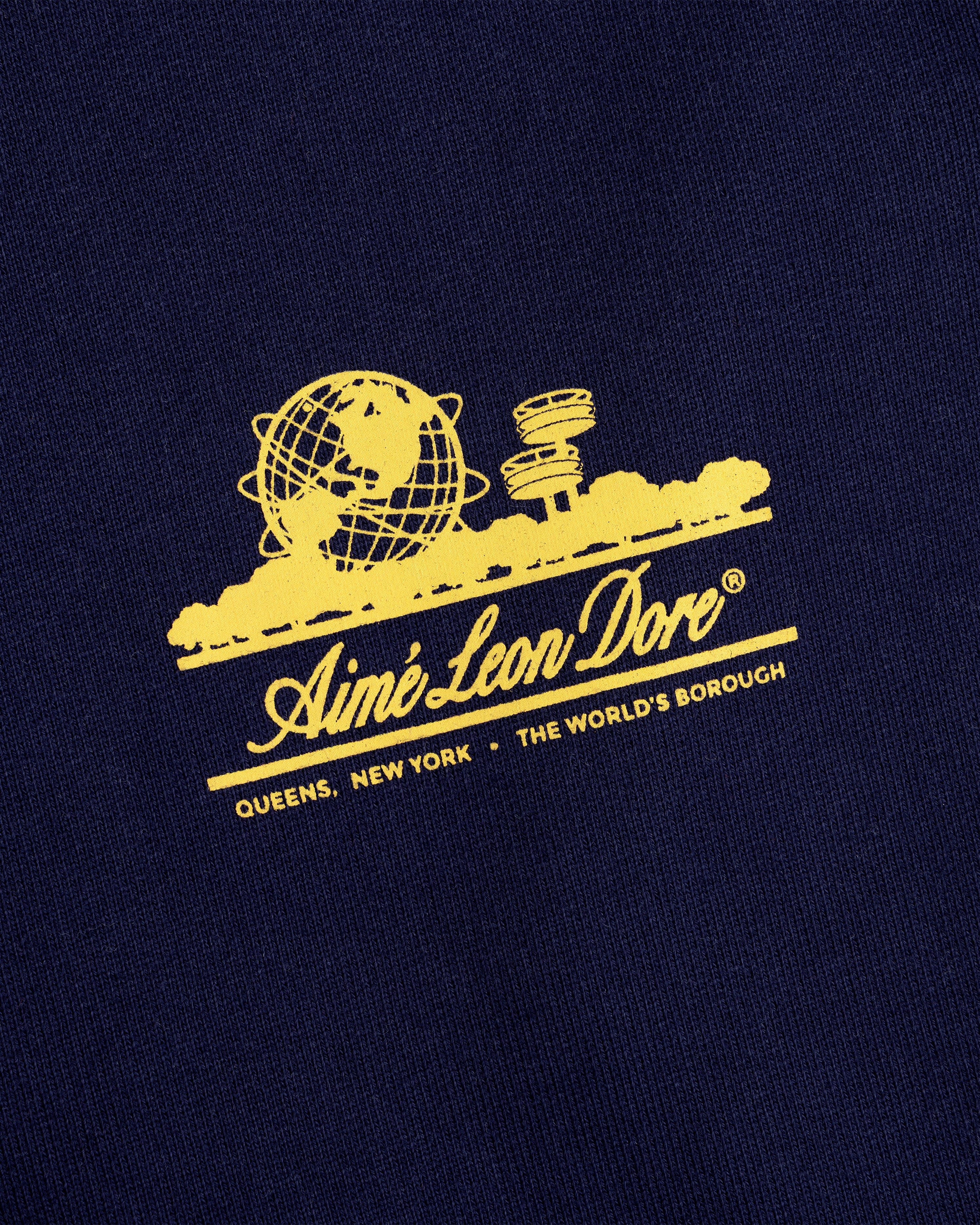 Yellow Aimé Leon Dore globe and text on navy blue Unisphere Sweatpants, referencing Queens, New York.