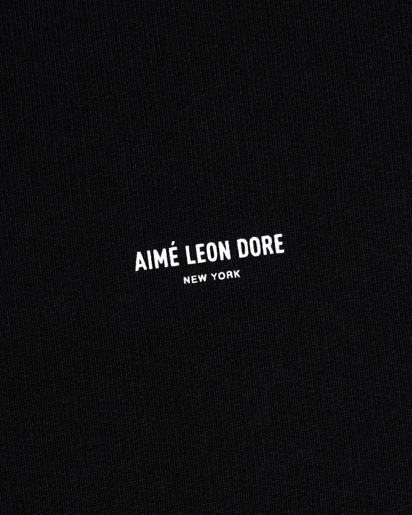 Black Micro Logo Crewneck Sweatshirt with small white "AIMÉ LEON DORE NEW YORK" text centered on fabric.