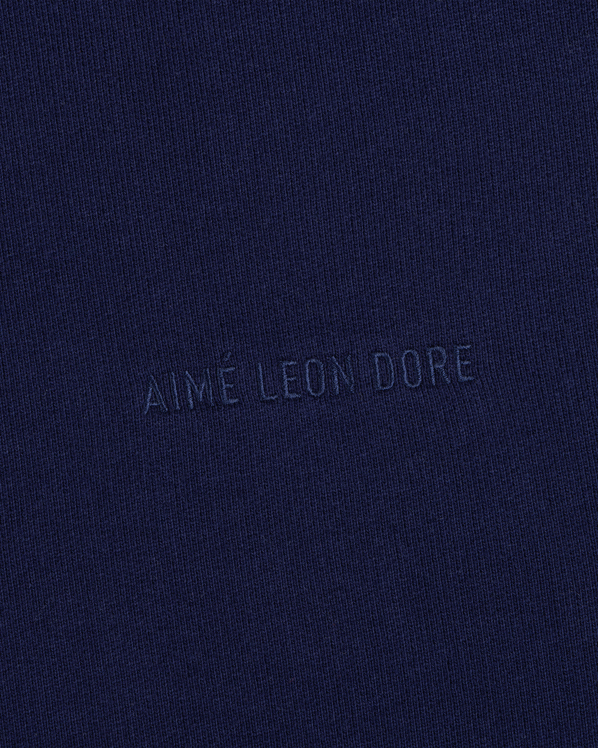Close-up of navy blue Tonal Logo Crewneck Sweatshirt with AIMÉ LEON DORE subtly embossed in the center.