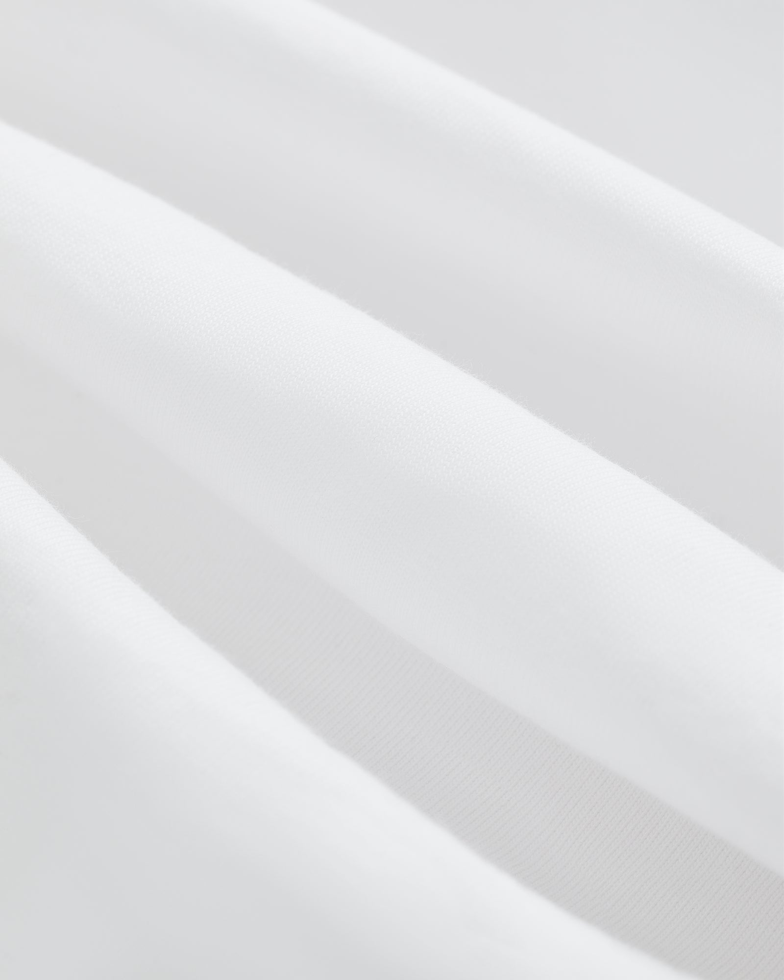Close-up of soft, white T-Shirt 3-Pack fabric with gentle folds for a smooth, clean texture.