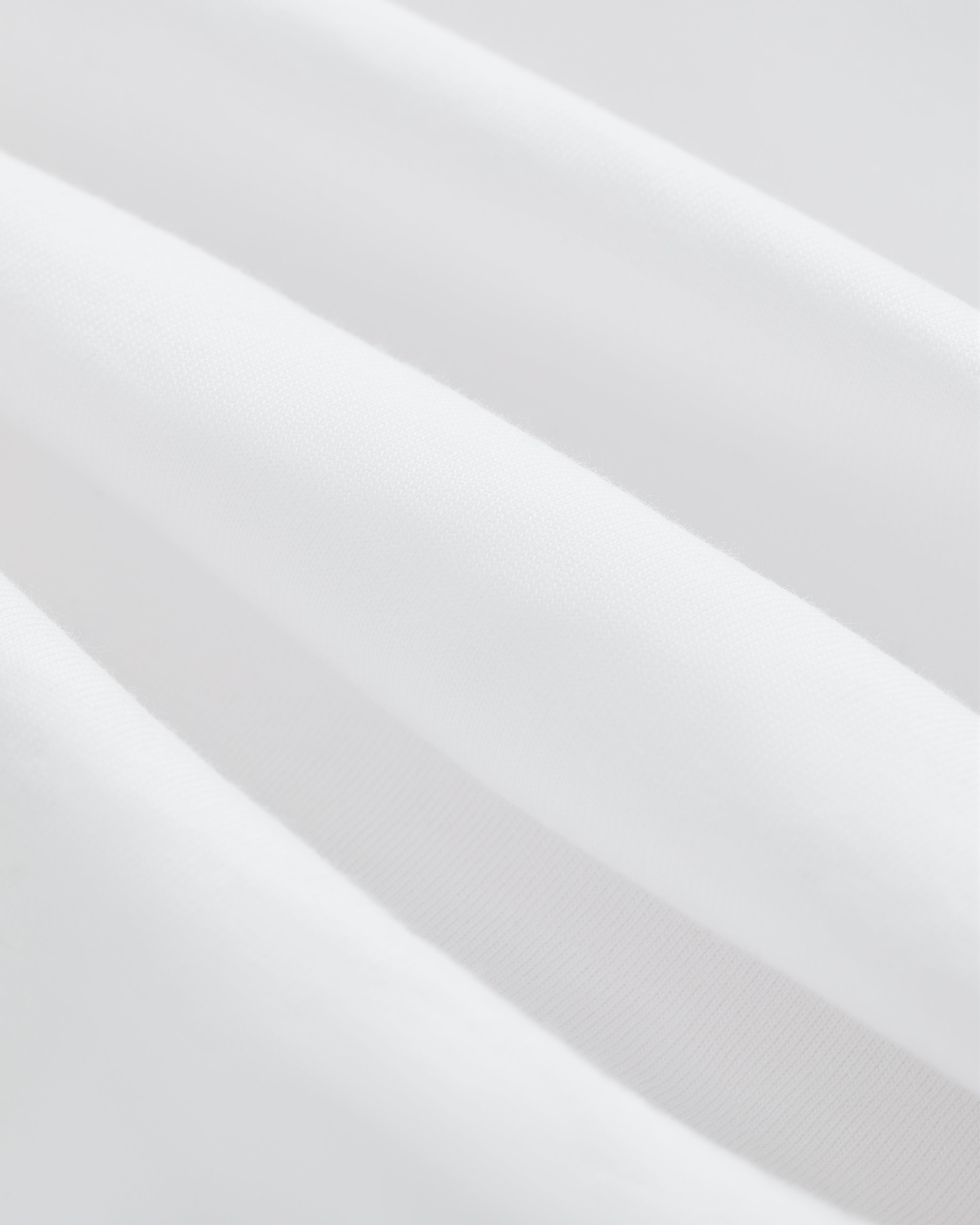 Close-up of soft, white T-Shirt 3-Pack fabric with gentle folds for a smooth, clean texture.